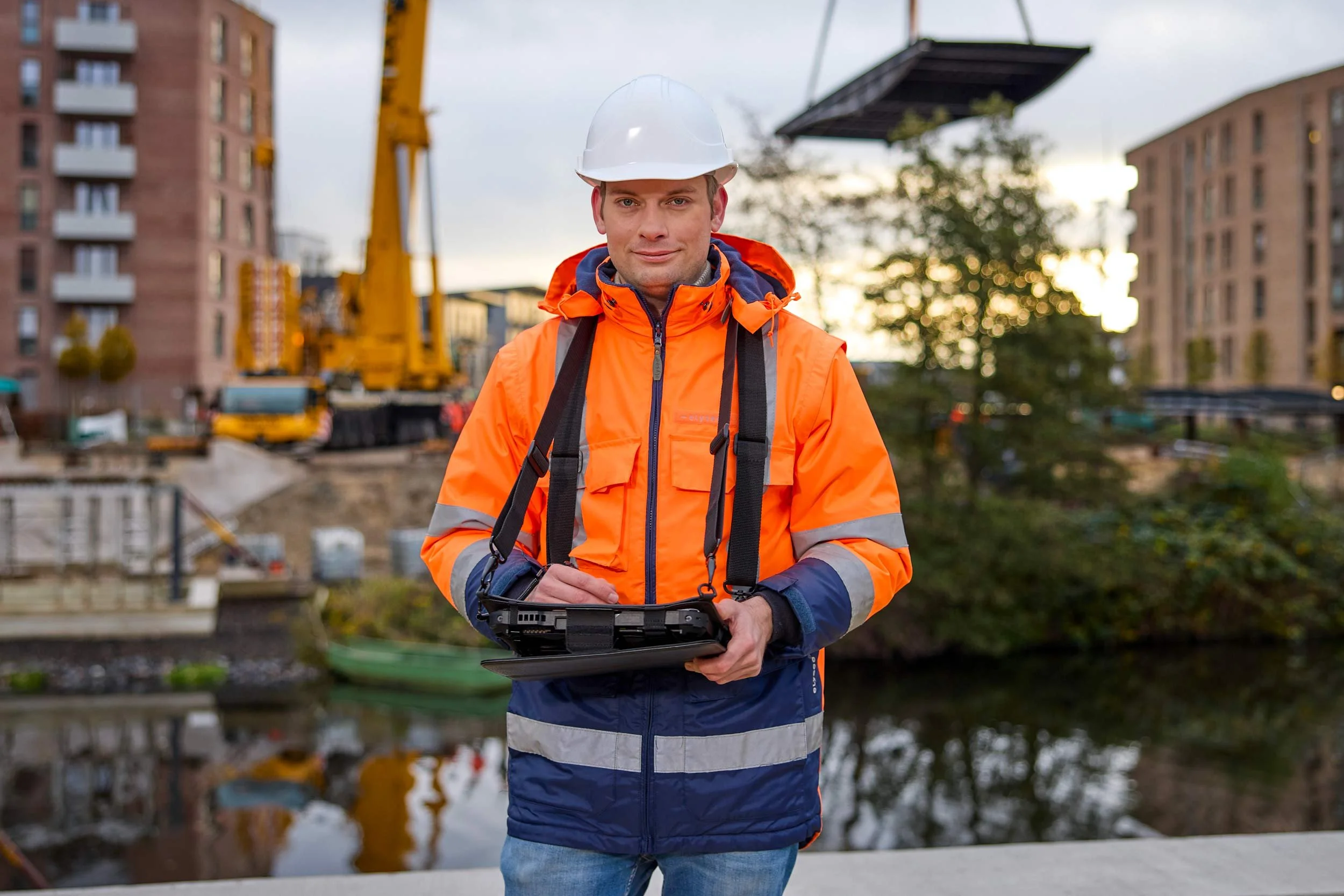 Bauingenieur mit Schutzhelm und Tablet auf einer Baustelle am Hafen in Hamburg