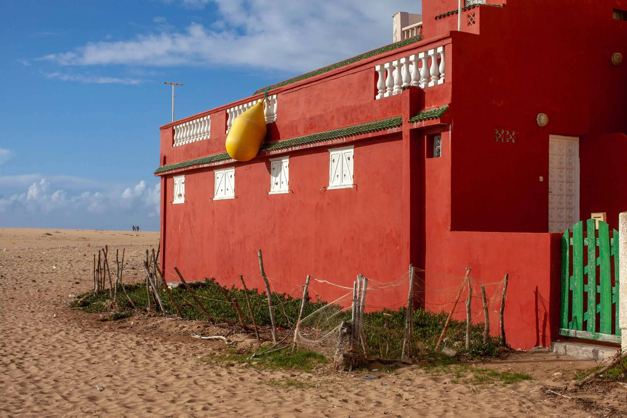 Rotes haus am strand mit gelbem bojenkoerper an der fassade in marokko