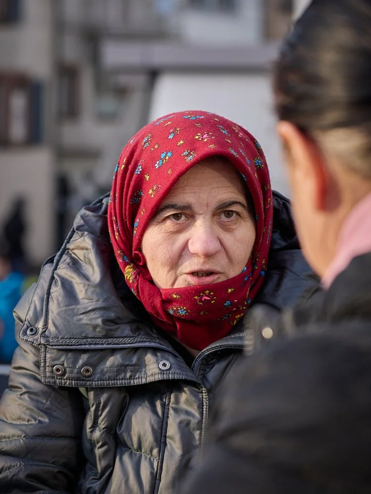 Eine Frau mit Kopftuch spricht mit einer weiteren Person auf der Strasse.