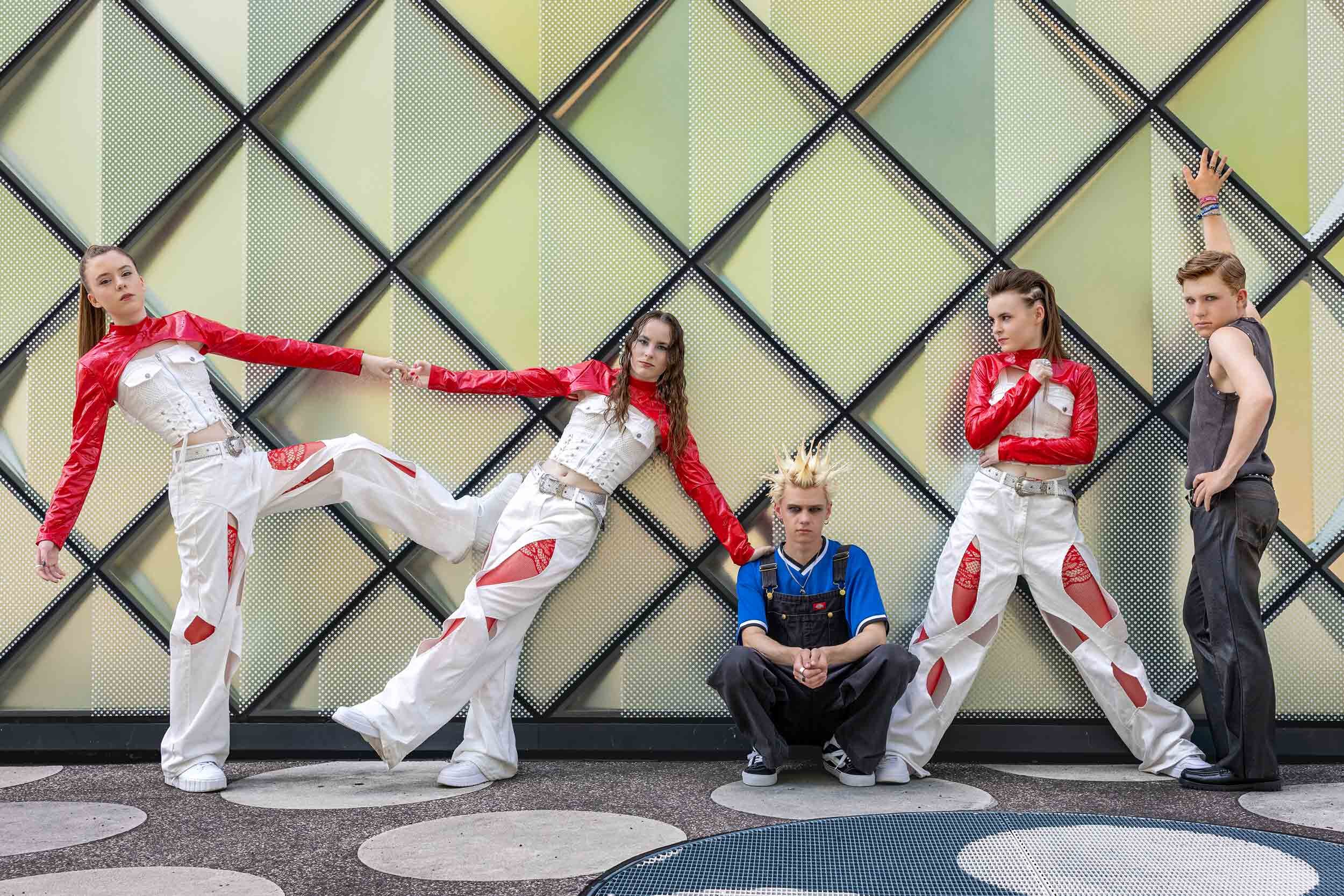 Fünf Mitglieder der Band III RIØT posieren vor der geometrischen Fassade des Futuriums in Berlin.