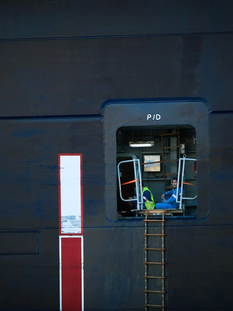 Zwei Schiffsarbeiter in einem Einstieg eines Frachtschiffs im Hamburger Hafen