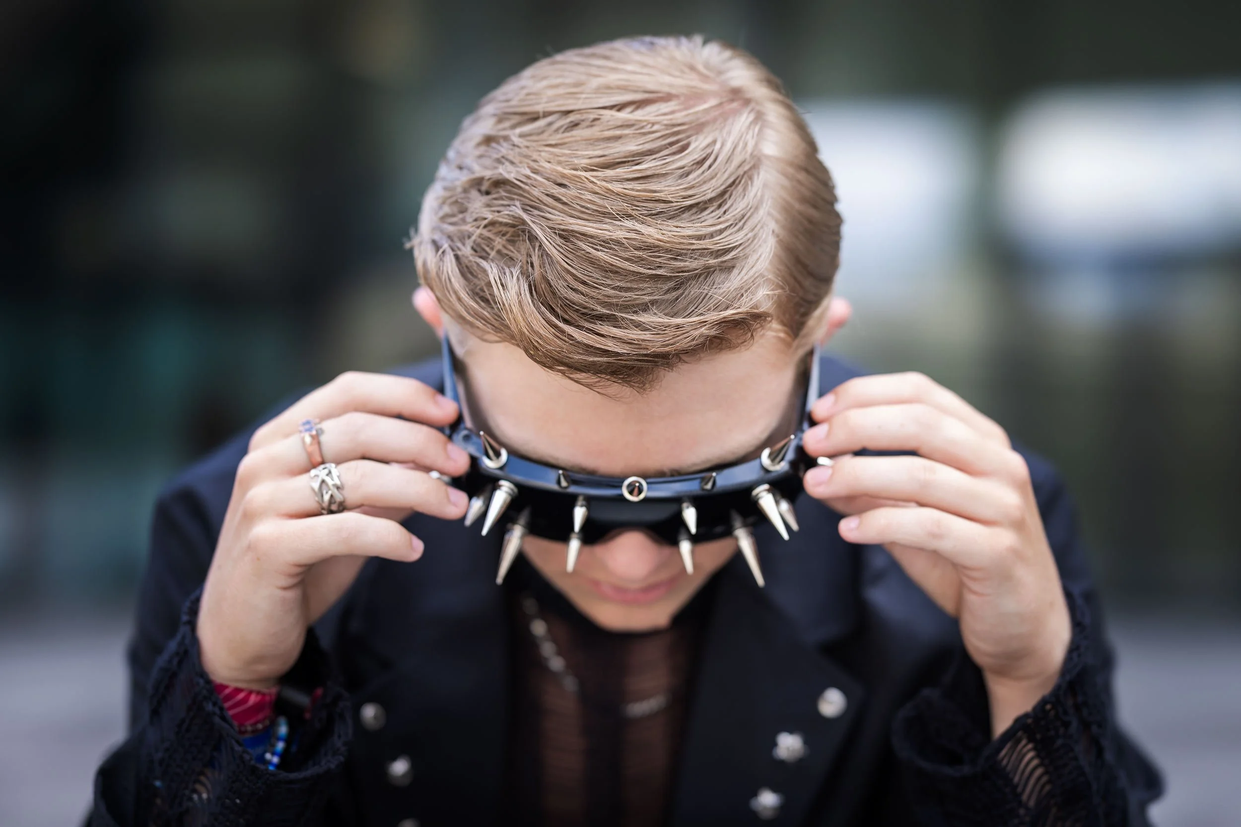 Mitglied der Band III RIØT setzt eine schwarze Sonnenbrille mit Metallspitzen auf. Aufnahme vor dem Futurium in Berlin.