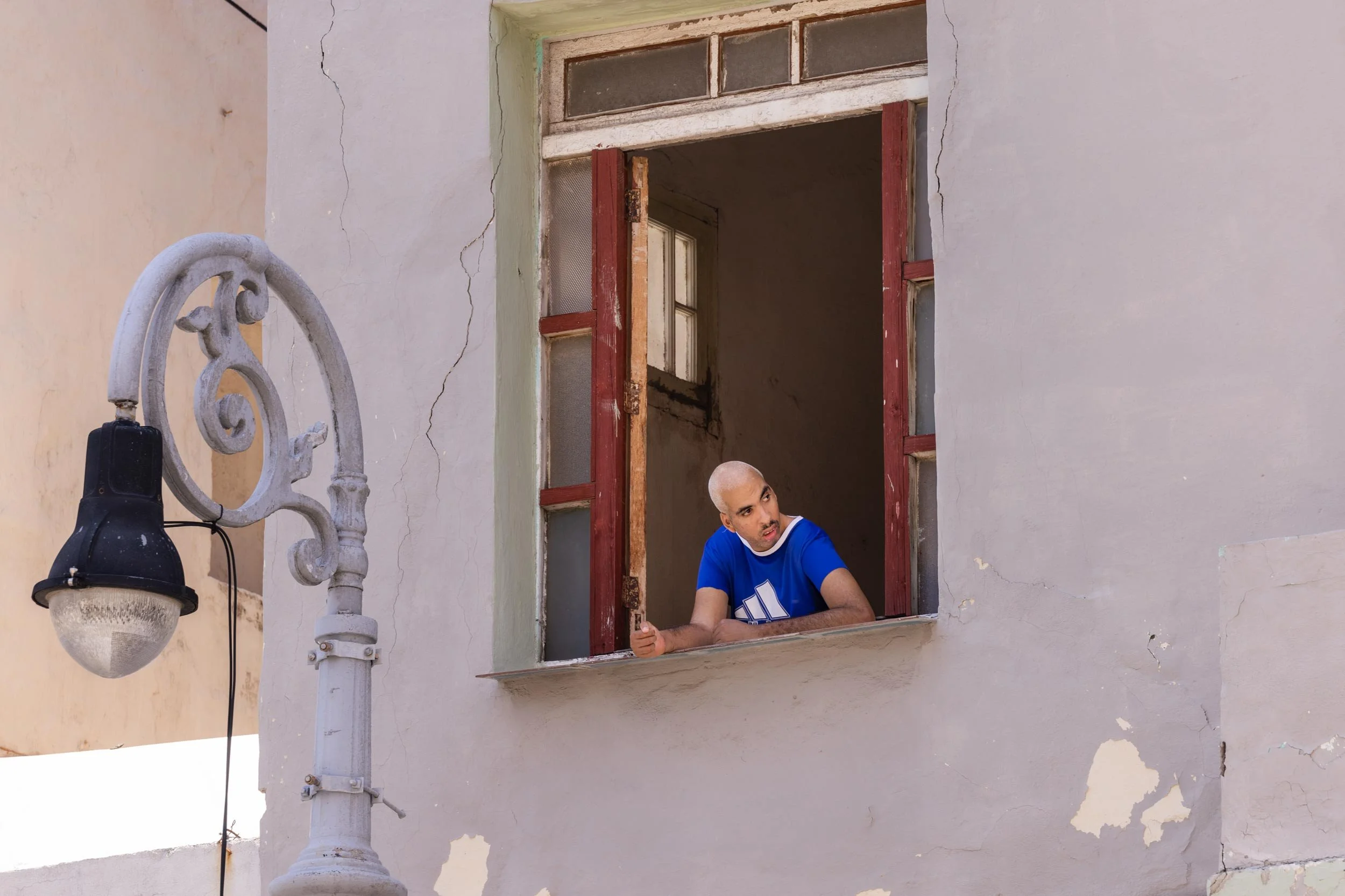 Mann lehnt sich aus einem offenen Fenster eines Altbaus und blickt nach draußen