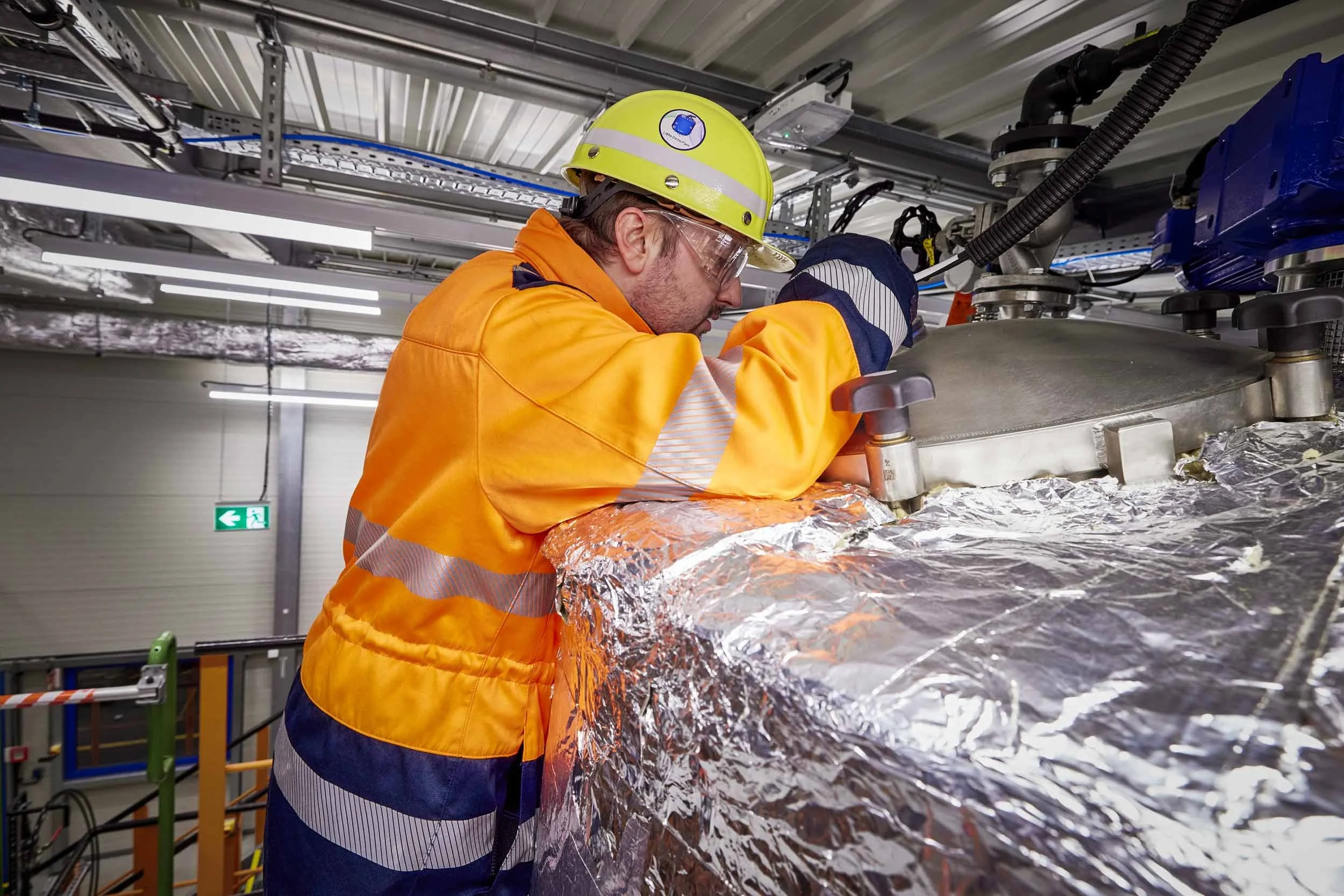 Präzise Handarbeit am Reaktor: Ein Techniker kontrolliert das System – Know-how trifft auf Hightech in anspruchsvoller Umgebung.