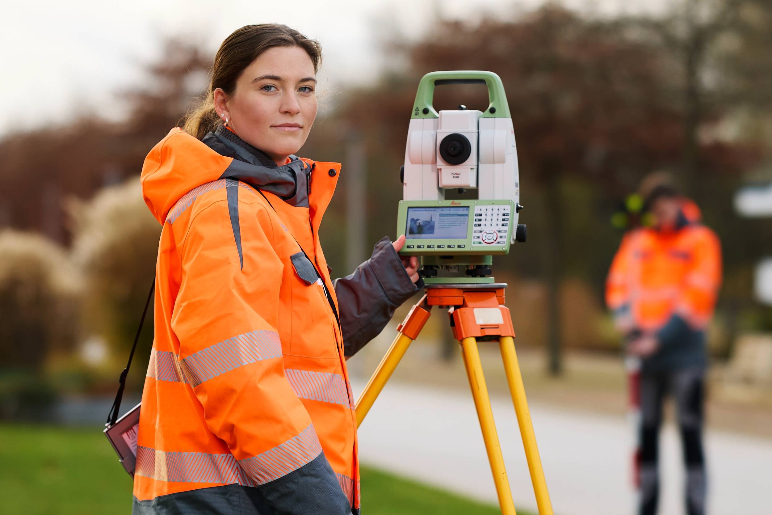 Vermessungstechnikerin mit Totalstation bei einer Vermessung im Außenbereich