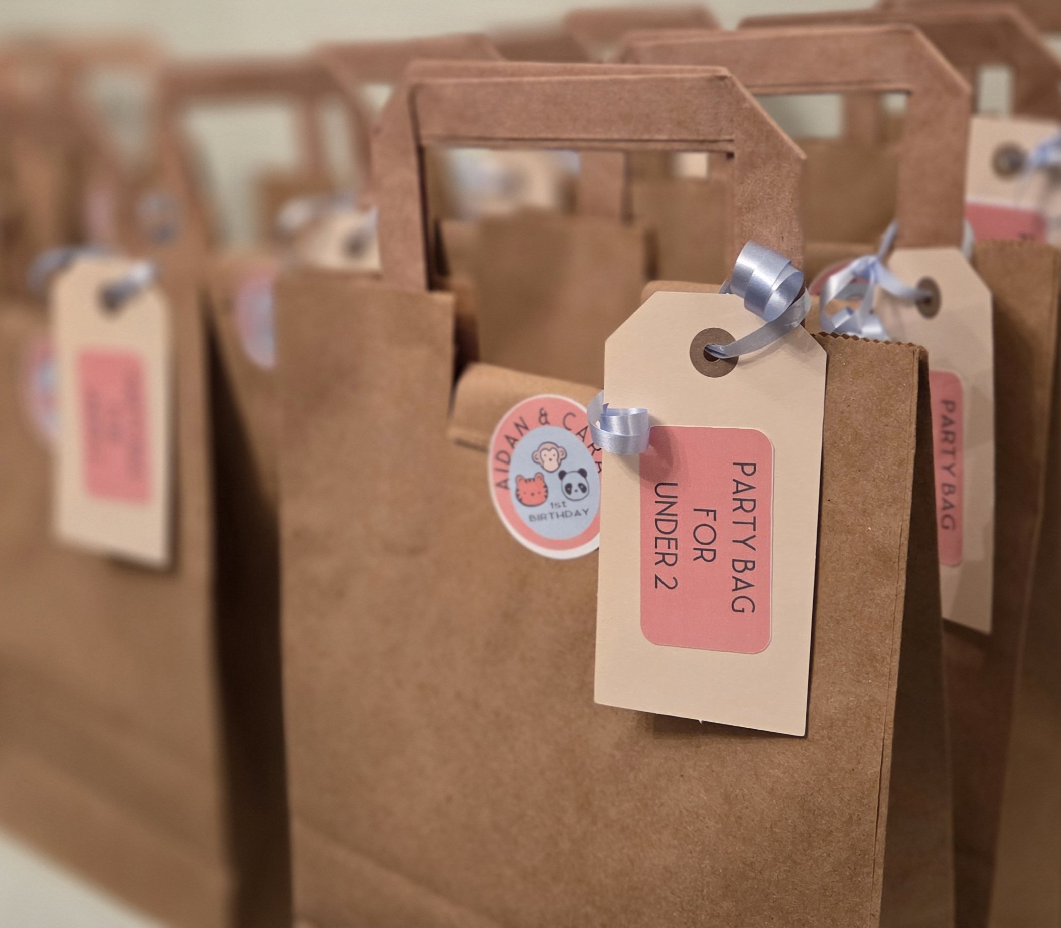 Close-up of multiple brown paper packages with hanging tags, some with logos of animals and birthday themes, arranged in an organized manner.