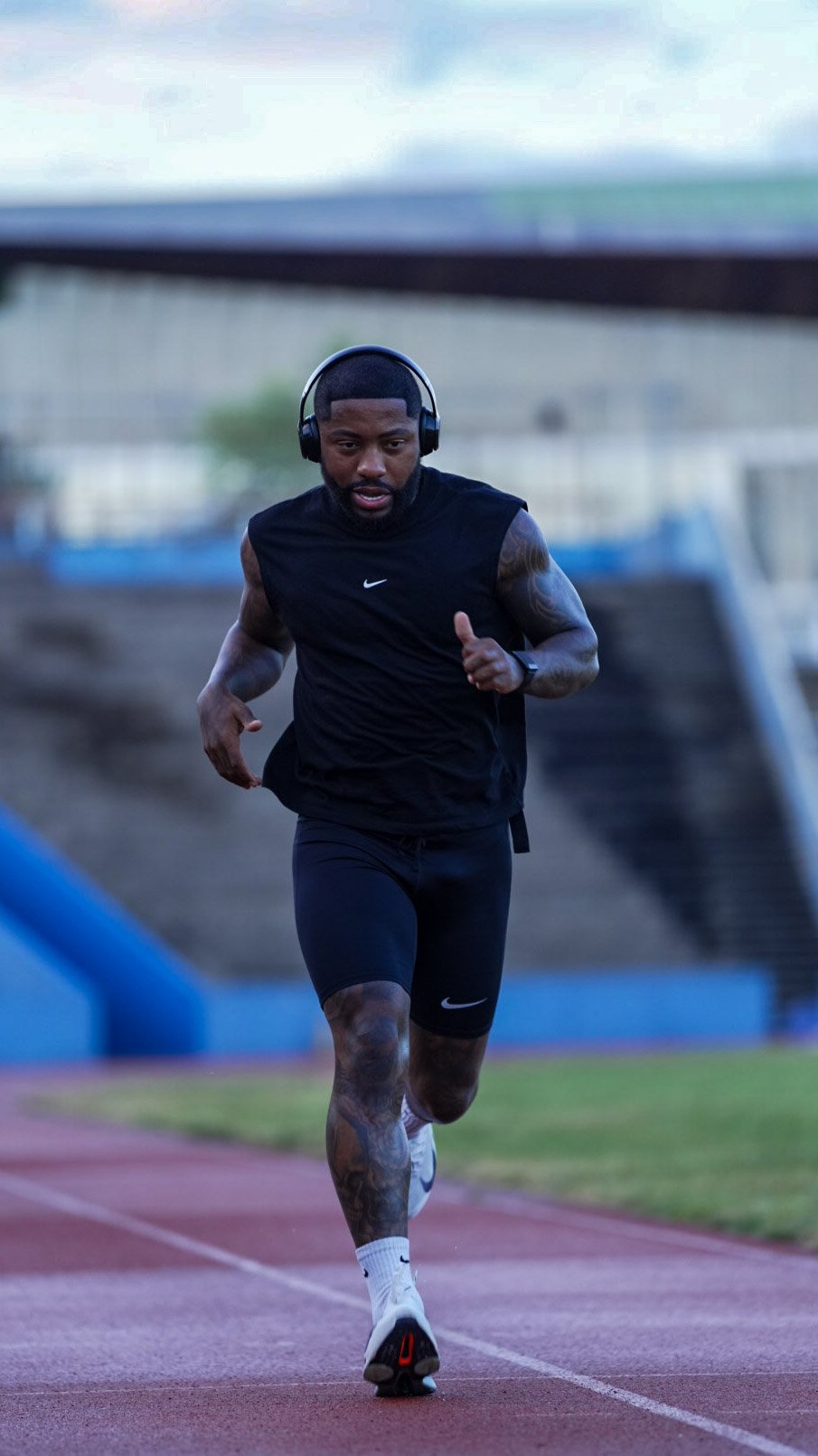 A man running on a track wearing headphones and athletic clothing.