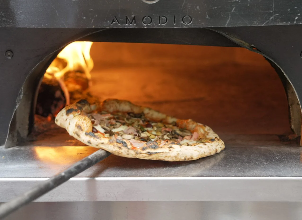 Pizza being baked in a wood-fired oven.