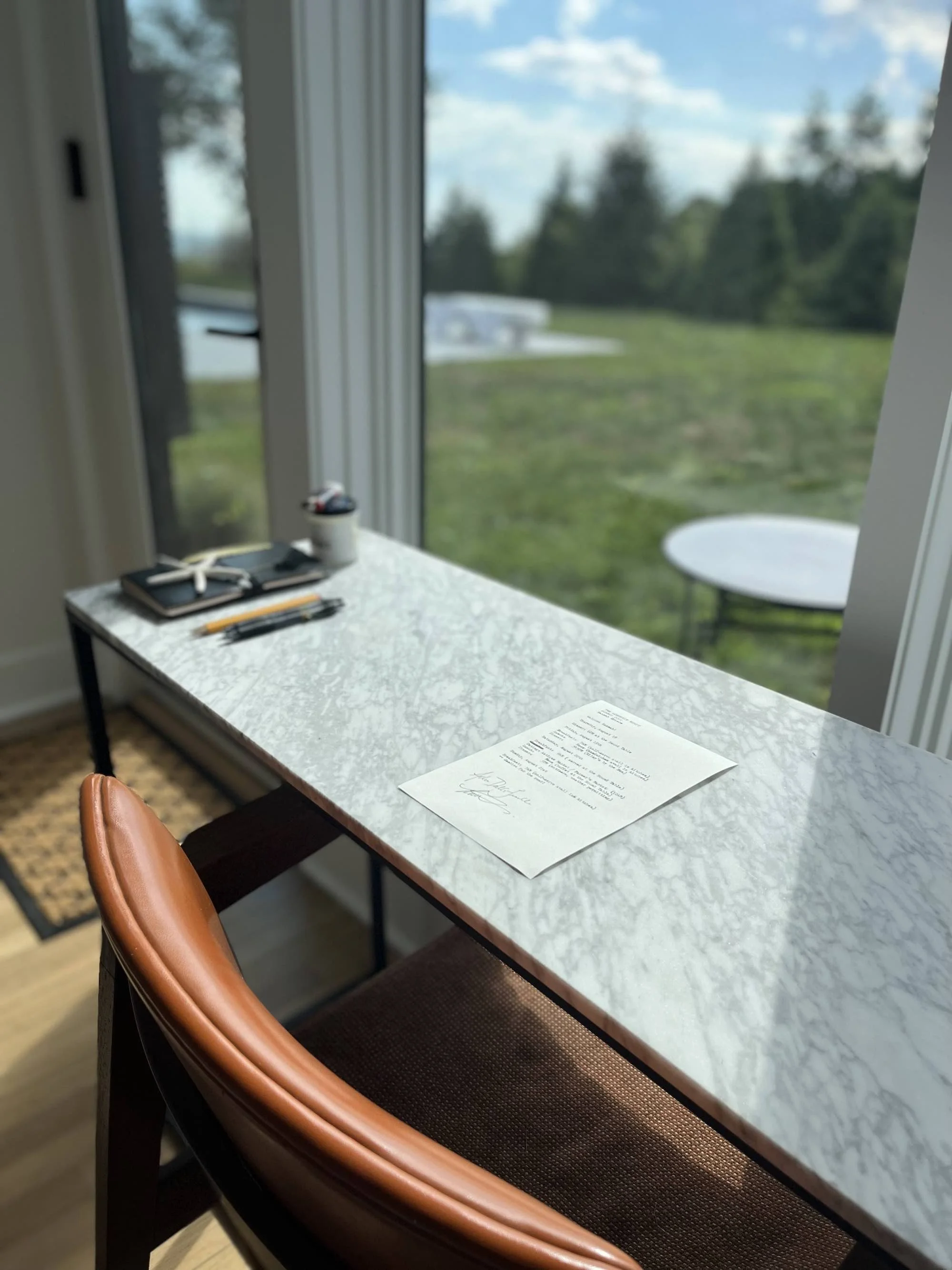 photo of Fellow's quarters desk and orange chair in front of sunlit window, overlooking green backyard; a typed letter is on the desk