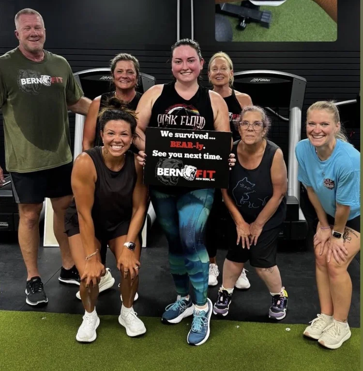 Group fitness class members posing together on the turf at Bern Fit