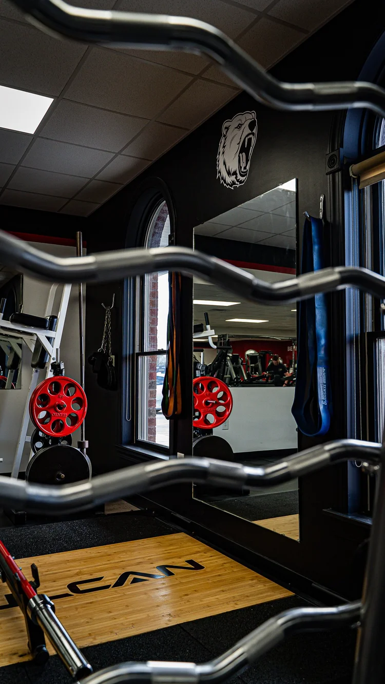 Curl bars on a rack beside a lifting platform at Bern Fit gym