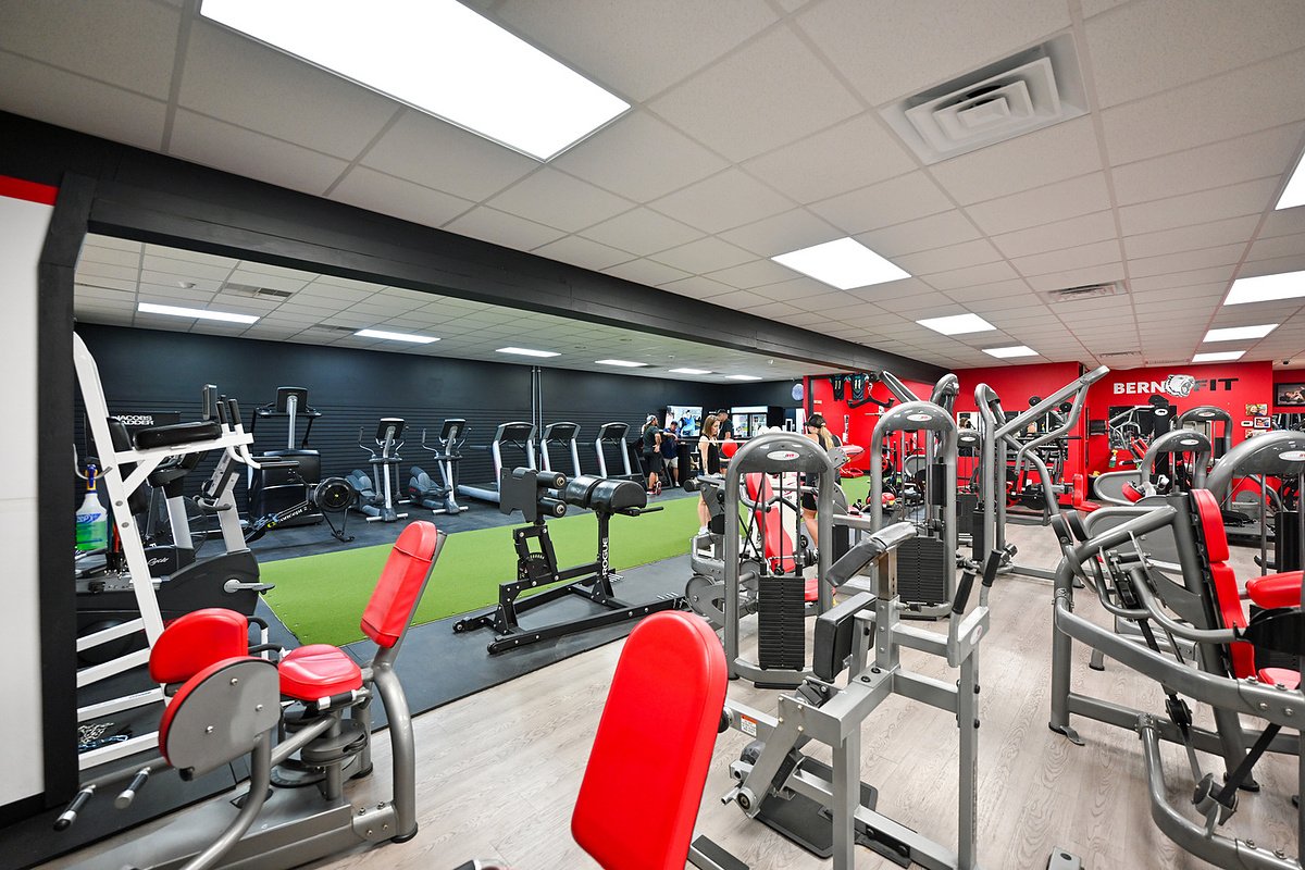 Red and gray strength machines beside the turf at Bern Fit gym