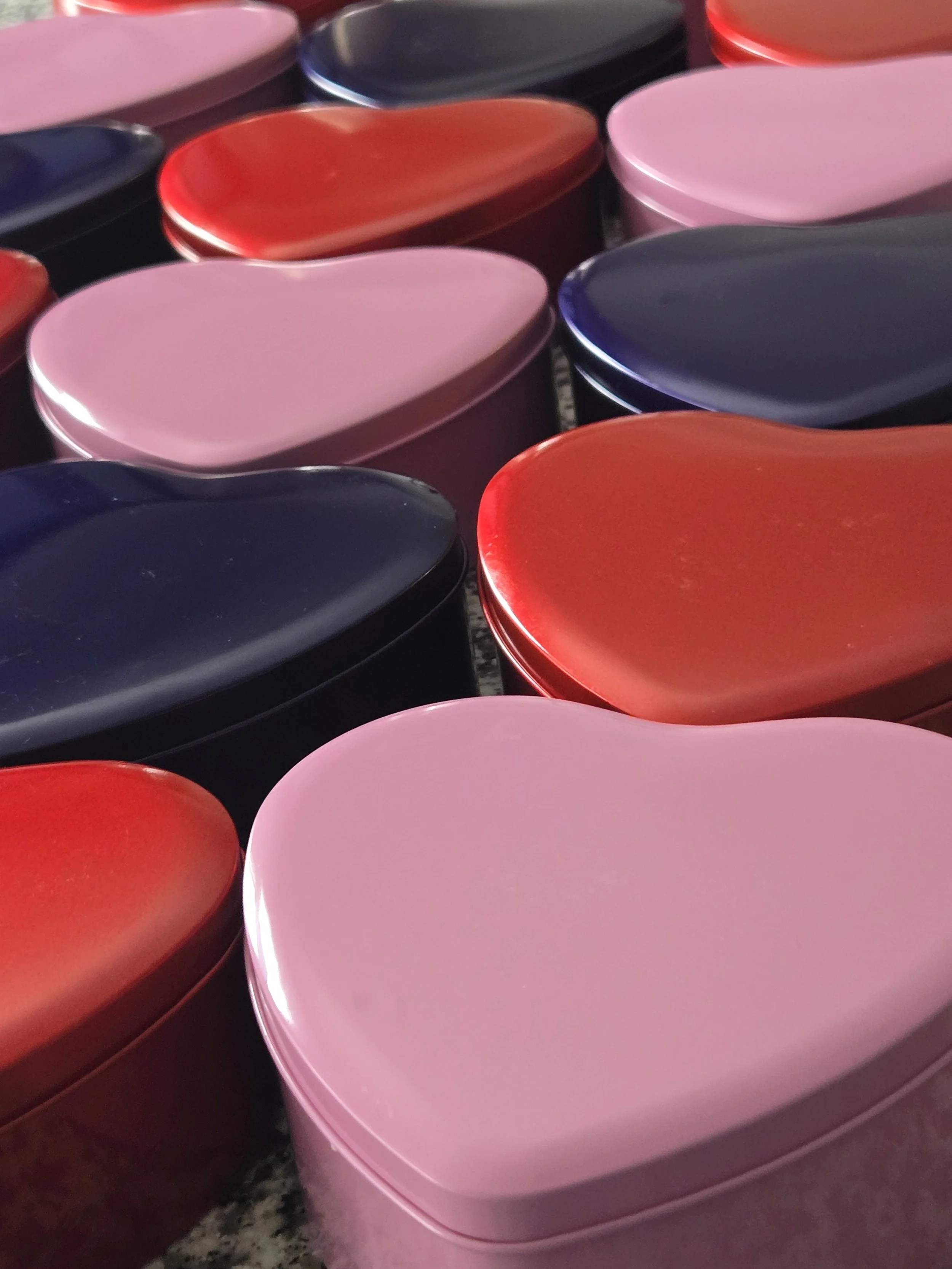 Heart-shaped tins in pink, red, and dark blue for memorable gifts and favors.