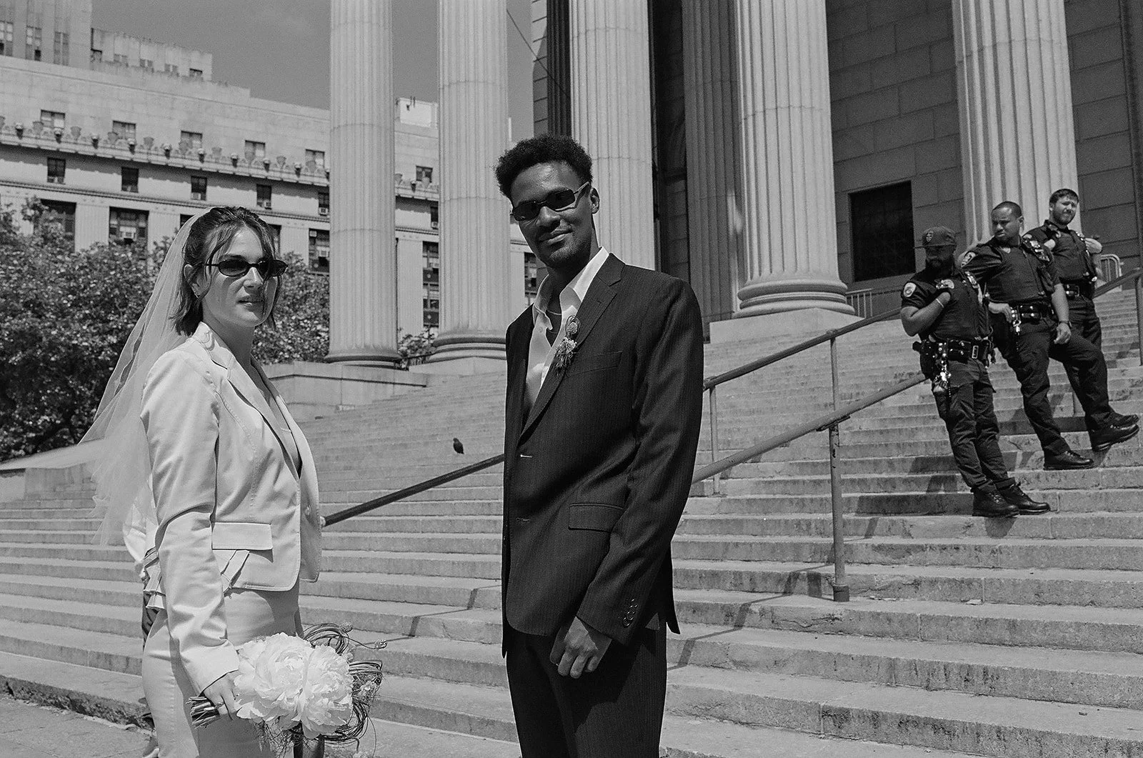 bride and groom at city hall with police officers chatting behind them in a row
