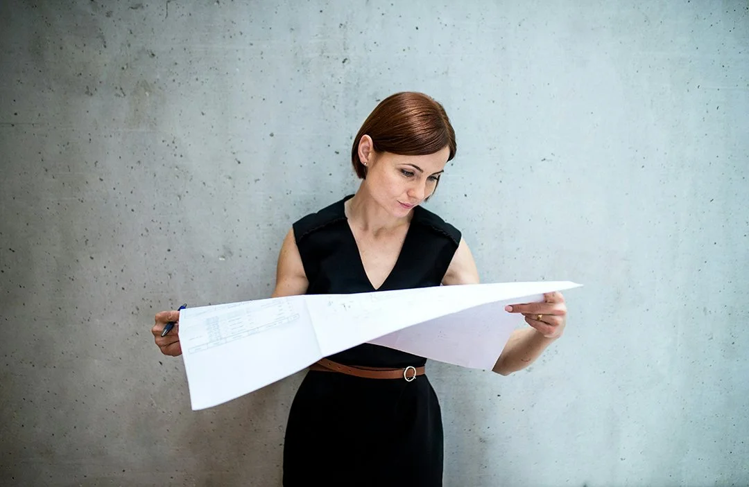 woman reading a large floor plan against concrete background