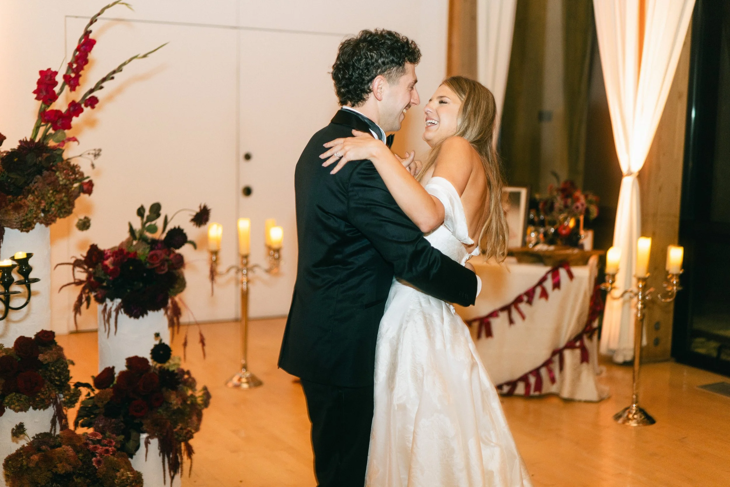 A bride and groom dancing at their wedding reception, smiling and embracing each other.