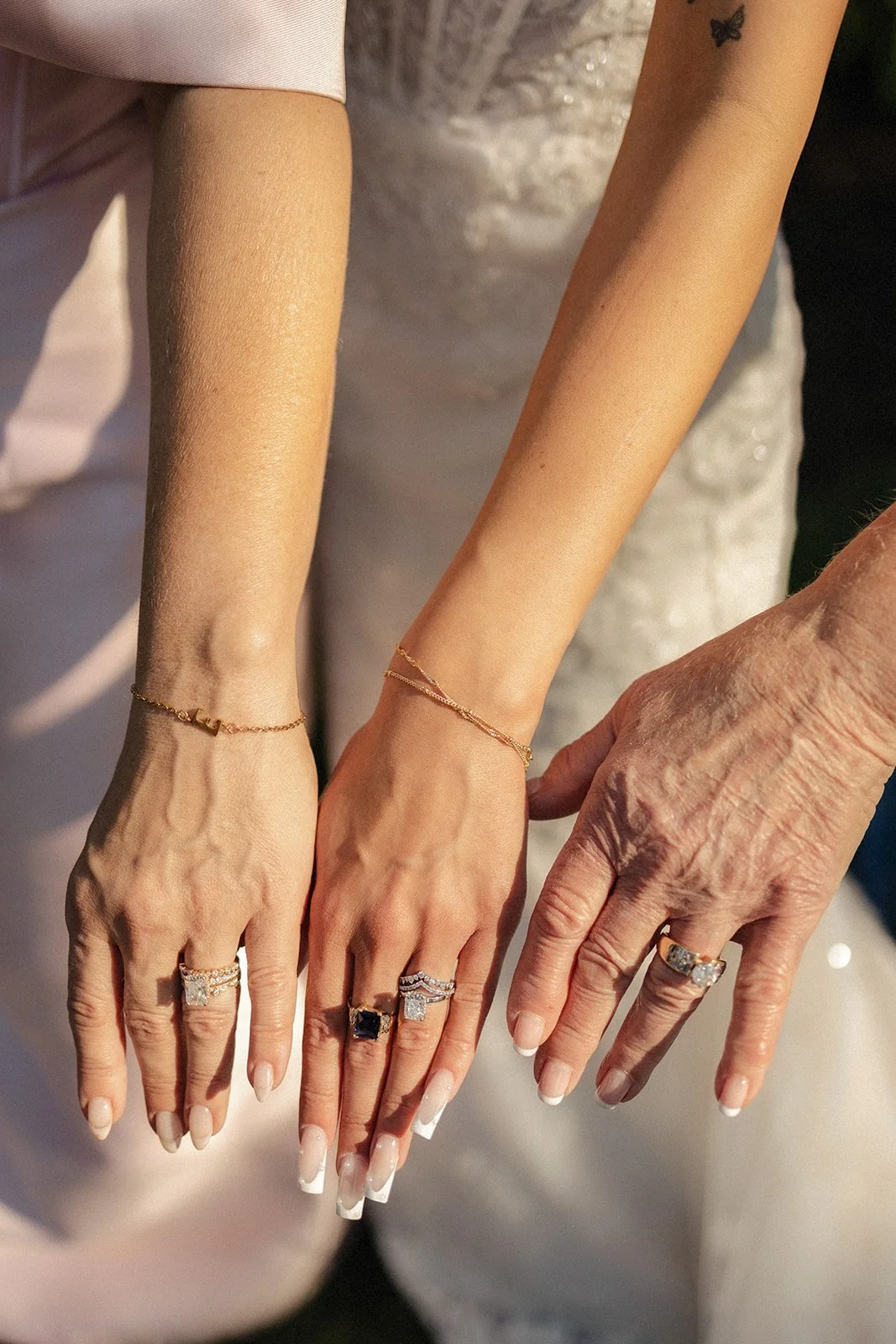 Close-up of four hands with rings and bracelets, displaying jewelry. The hands belong to different individuals, with varying skin tones and ages.