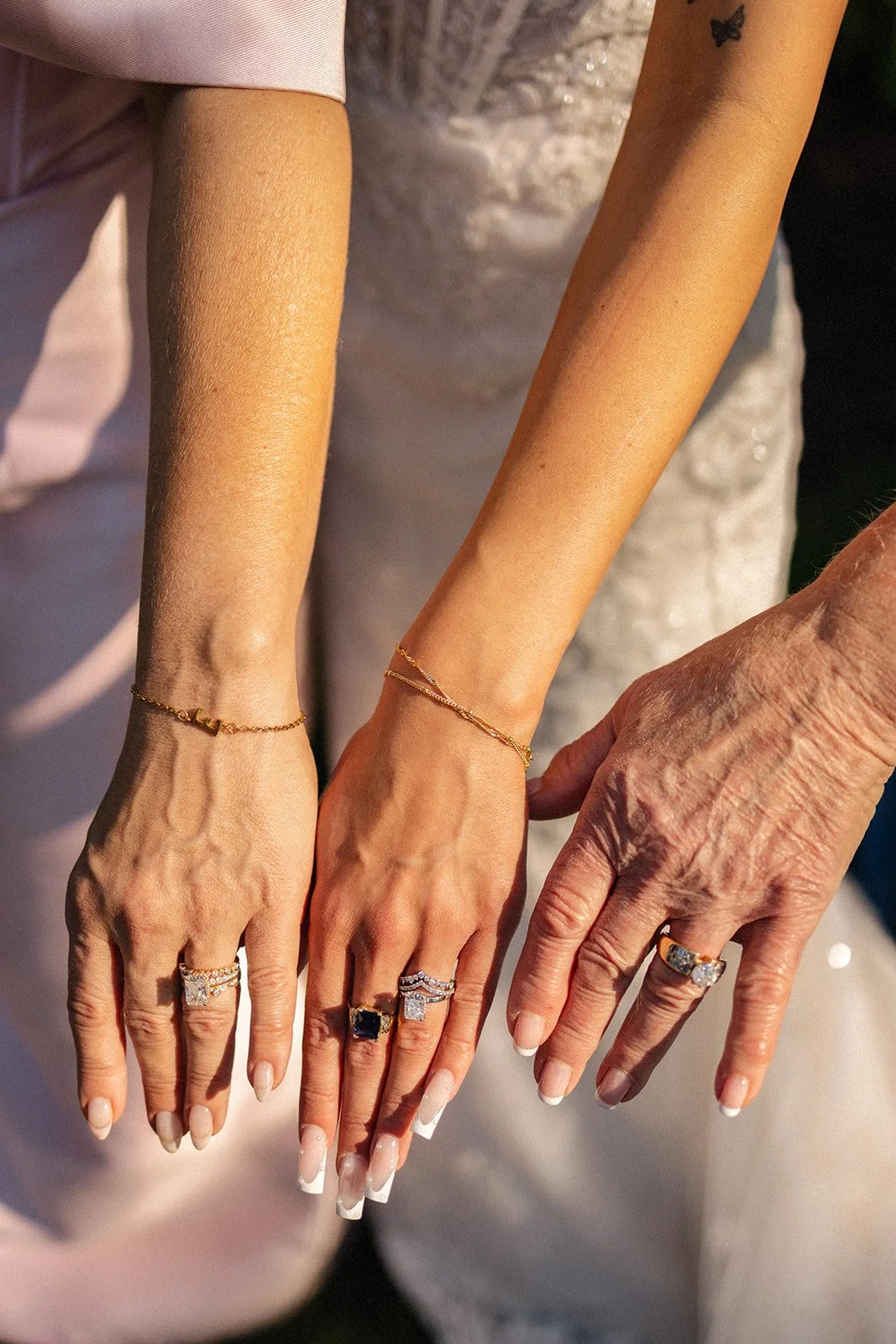 Close-up of three hands showing jewelry, including rings and bracelets, with a blurred background.
