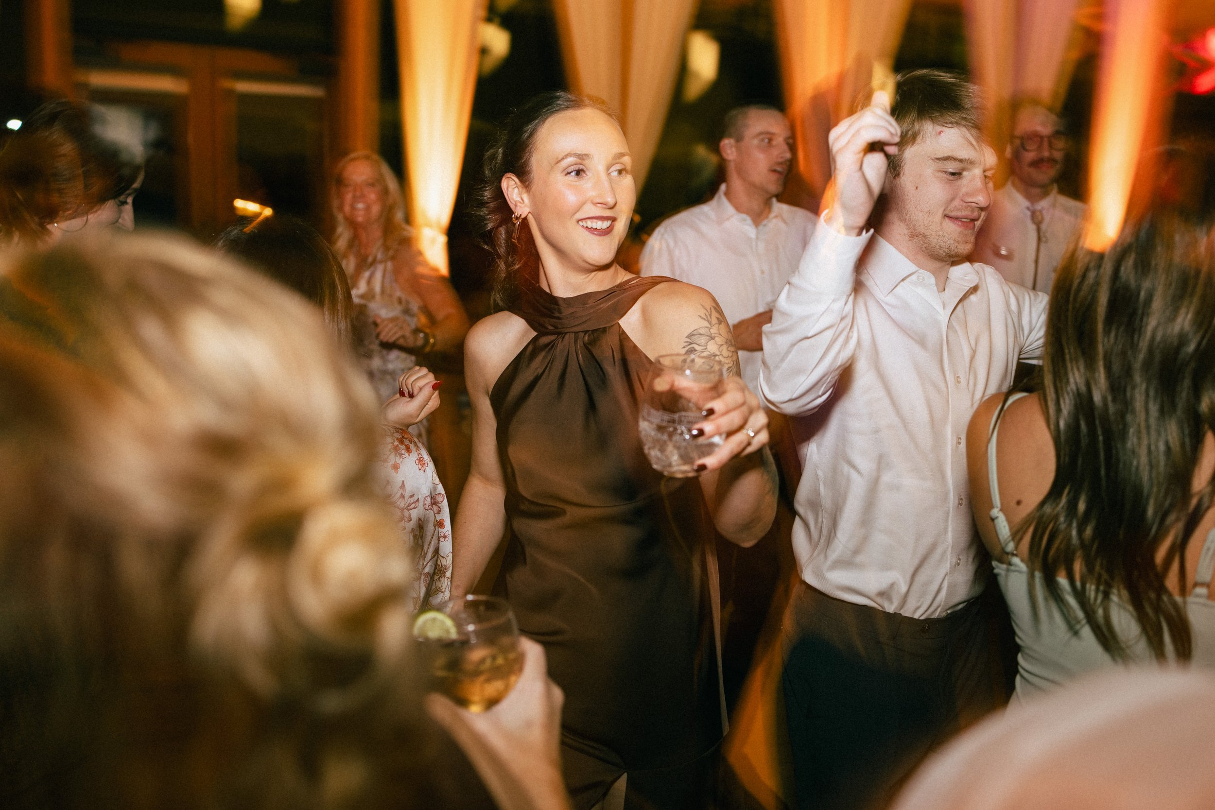 People dancing and enjoying themselves at a lively party or celebration in a warmly lit indoor venue.
