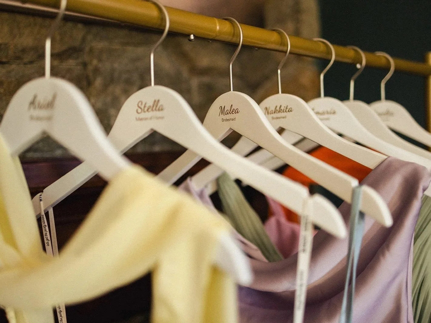 Clothes hanging on a rack with personalized tags, including names like 'Stella', 'Malea', and 'Nakkita'.