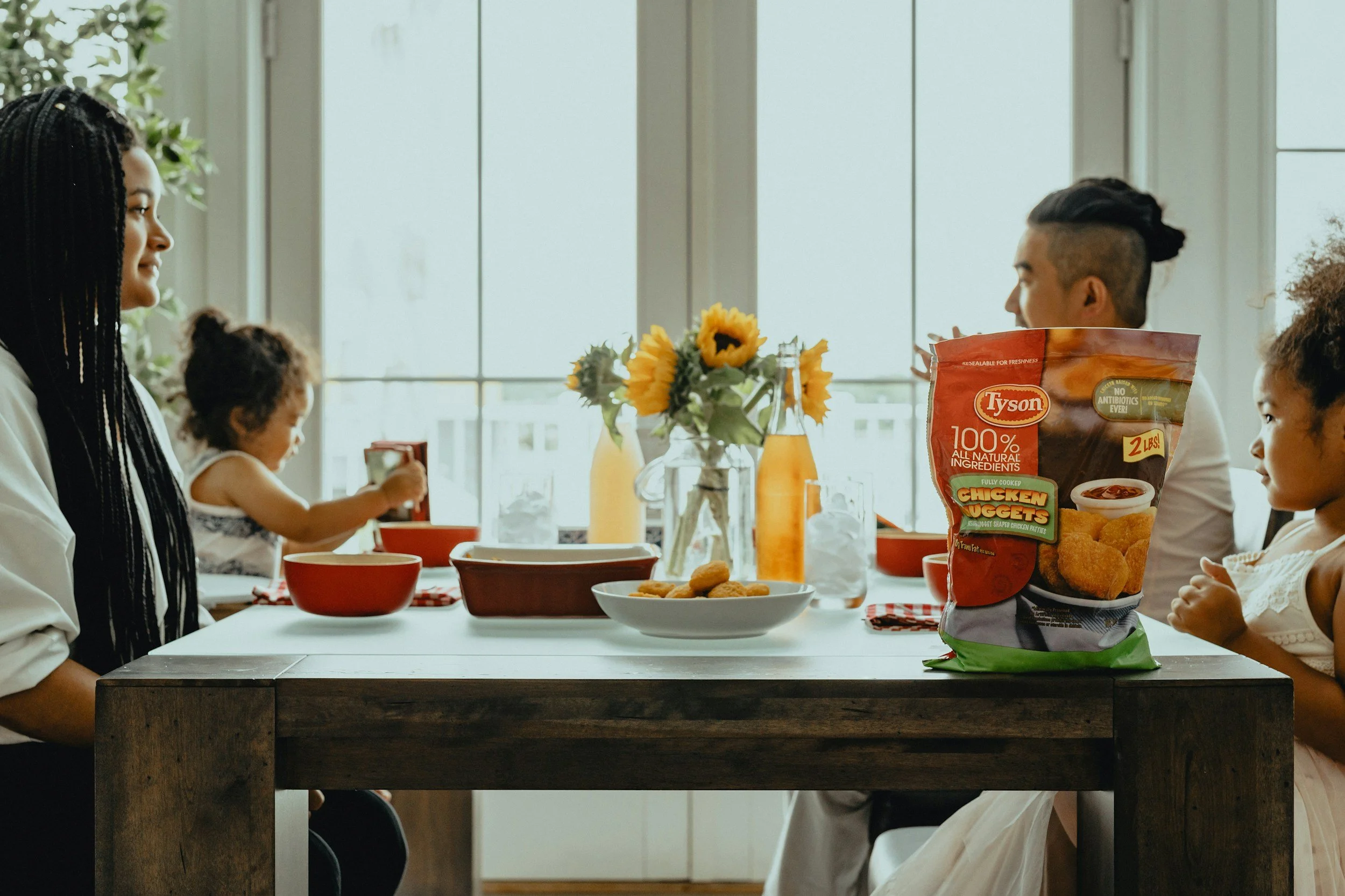 Family sitting together at a dining table, representing emotional safety, communication, and building a “We” family dynamic.