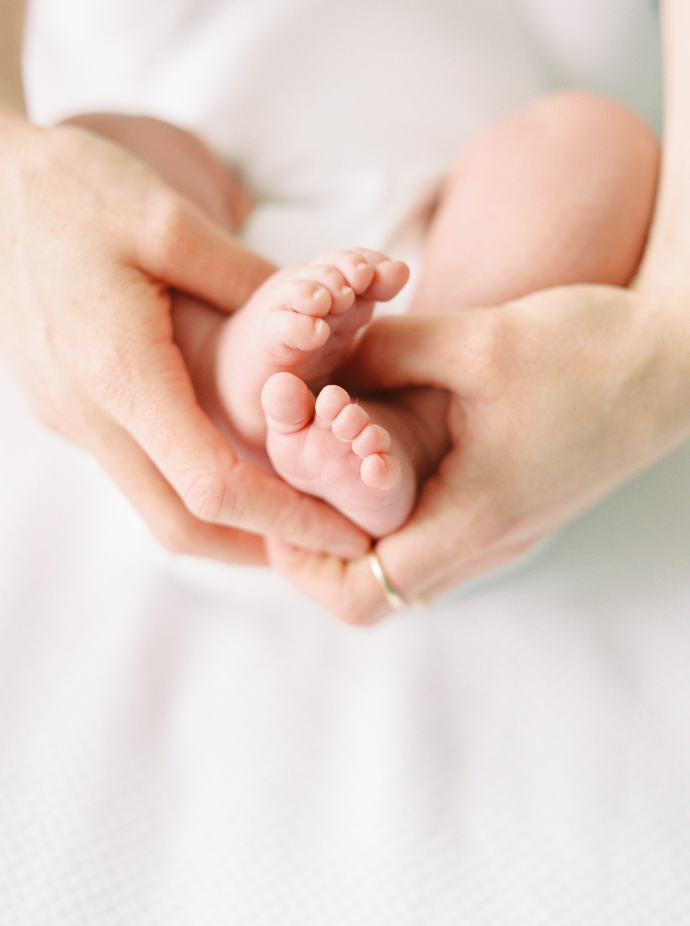 A woman's hands wrapped around baby's feet