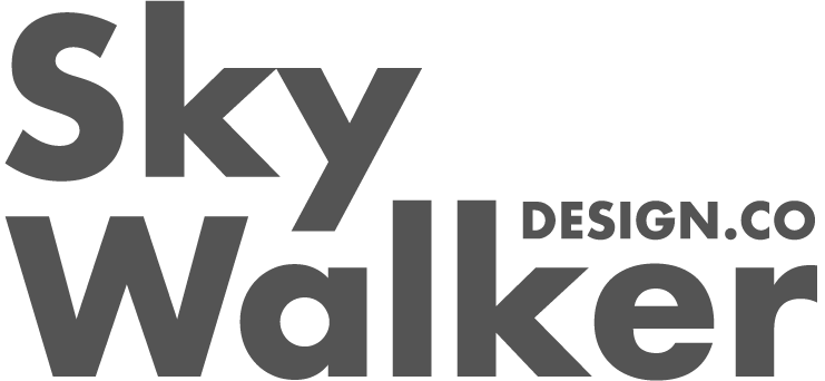 A person sitting at a desk working on a laptop with a cup and papers nearby.