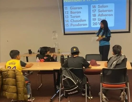 Group of diverse hands stacked, wearing colorful sweaters, symbolizing unity and teamwork.