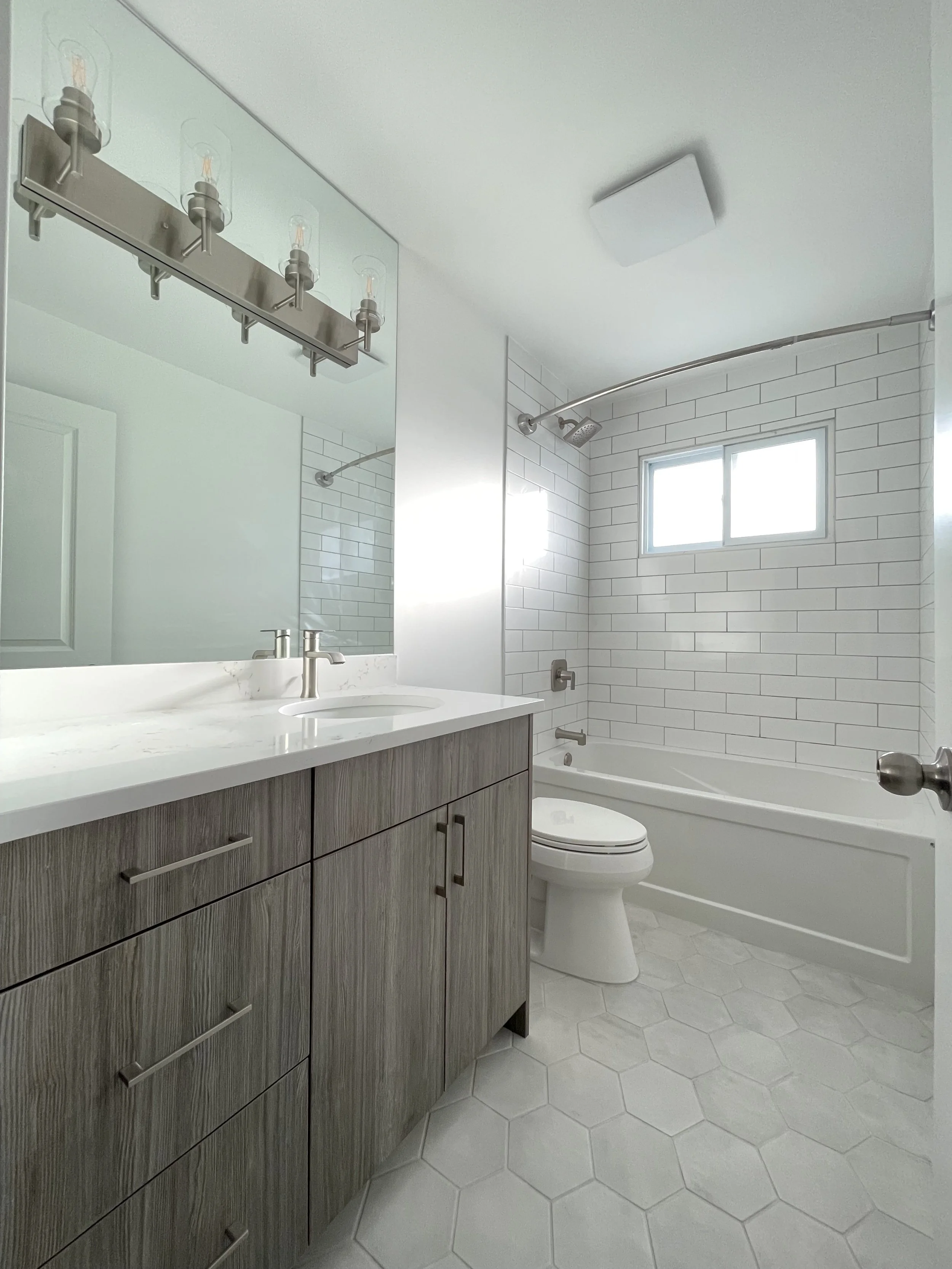 Calgary Renovation Contractor modern bathroom with subway tile shower, hexagon tile flooring, wood grain vanity, and quartz countertop