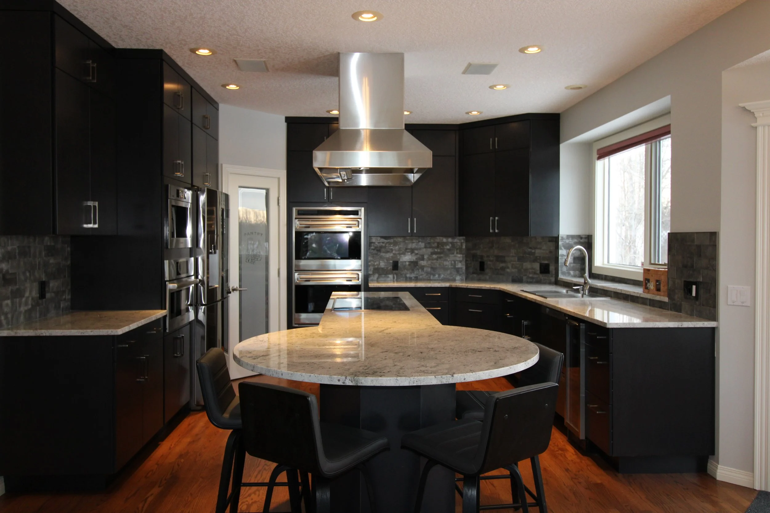 Calgary Renovation Contractor modern kitchen with black cabinetry, stainless steel appliances, granite countertops, and custom island design