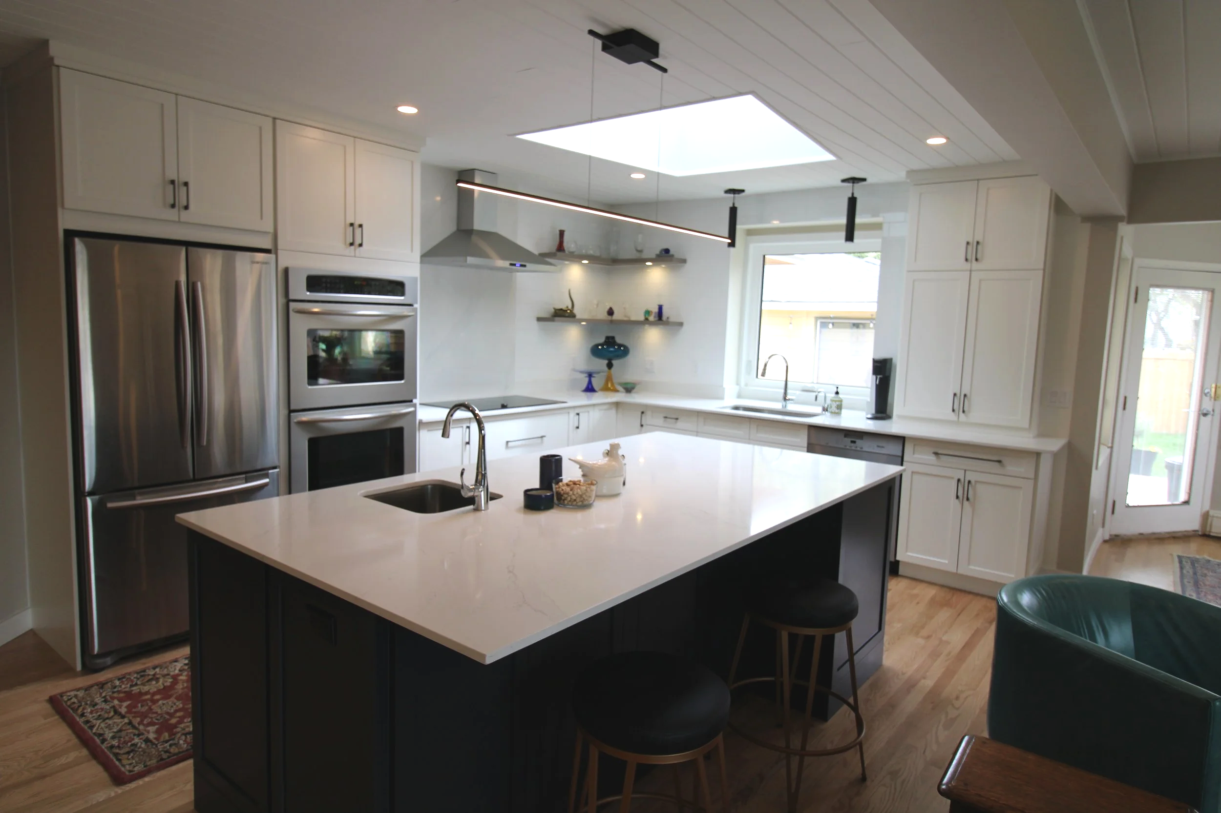 Calgary Renovation Contractor modern kitchen with quartz countertops, custom cabinetry, stainless steel appliances, and skylight design.