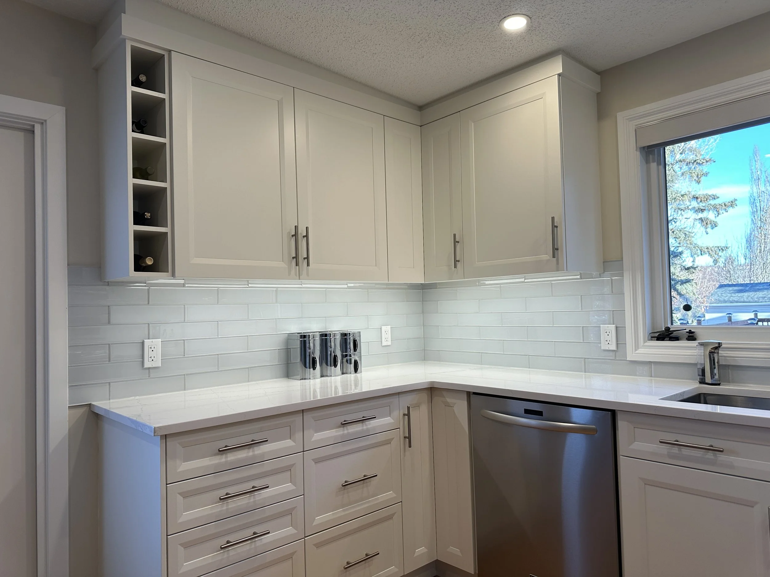 Calgary renovation contractor Dalhousie kitchen after renovation with custom cabinets, quartz countertops, and tile backsplash