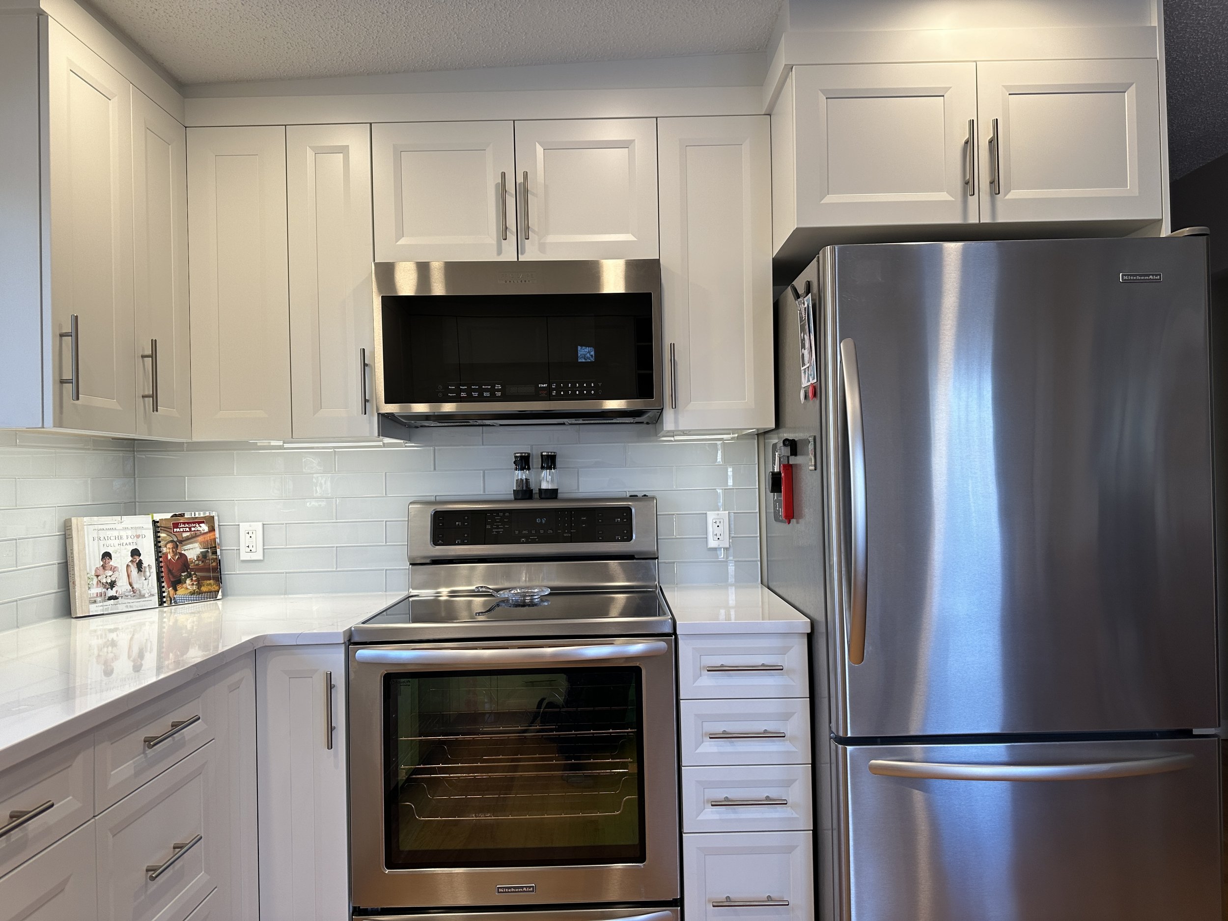 Calgary Renovation Contractor Dalhousie kitchen after renovation with modern white cabinetry and quartz countertops