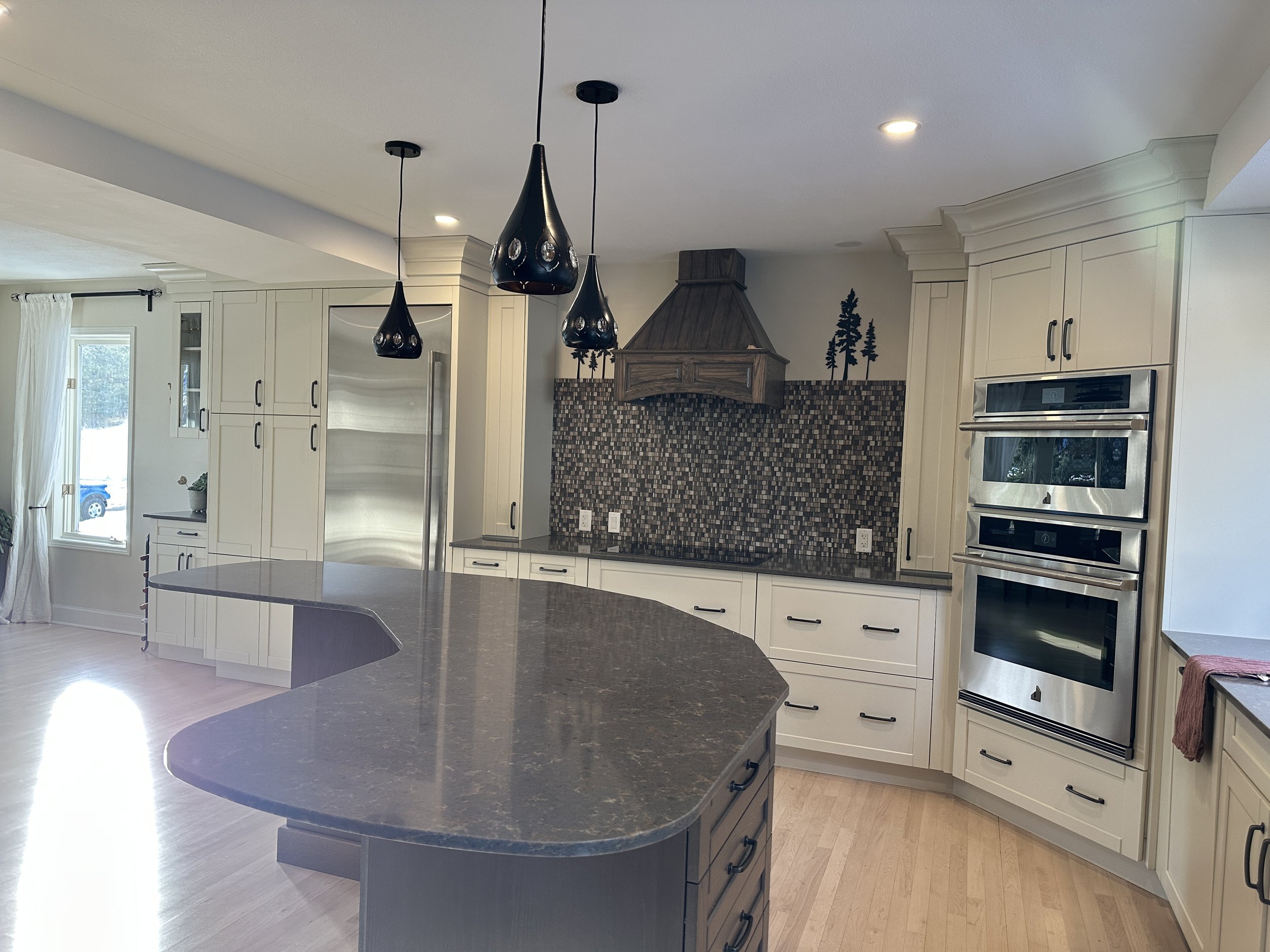After Canmore kitchen renovation with custom cabinetry, modern lighting, granite countertops, and luxury finishes.