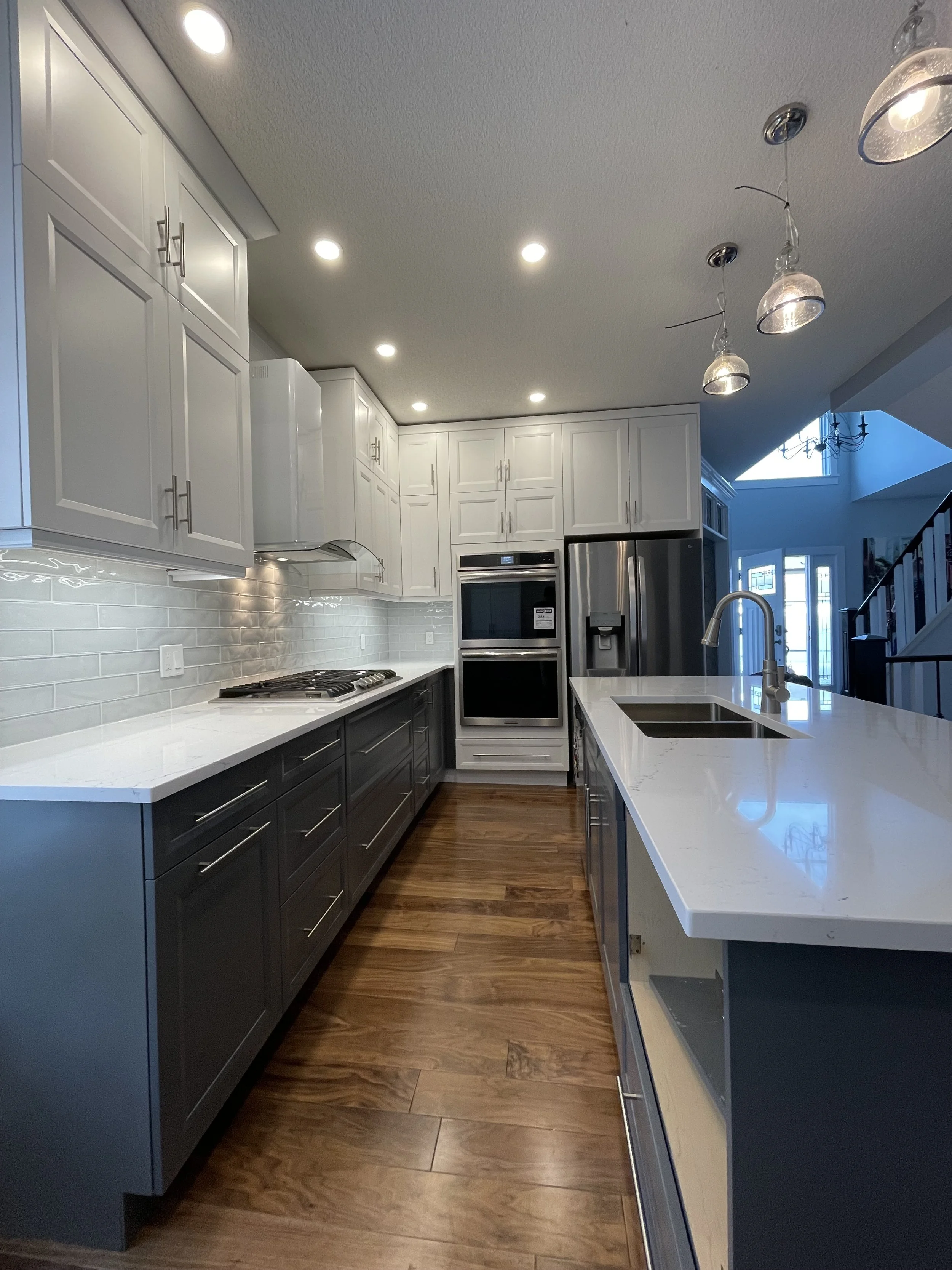 After photo of luxury Calgary kitchen renovation with white shaker cabinets, quartz countertops, and modern lighting – Terra Villa Developments