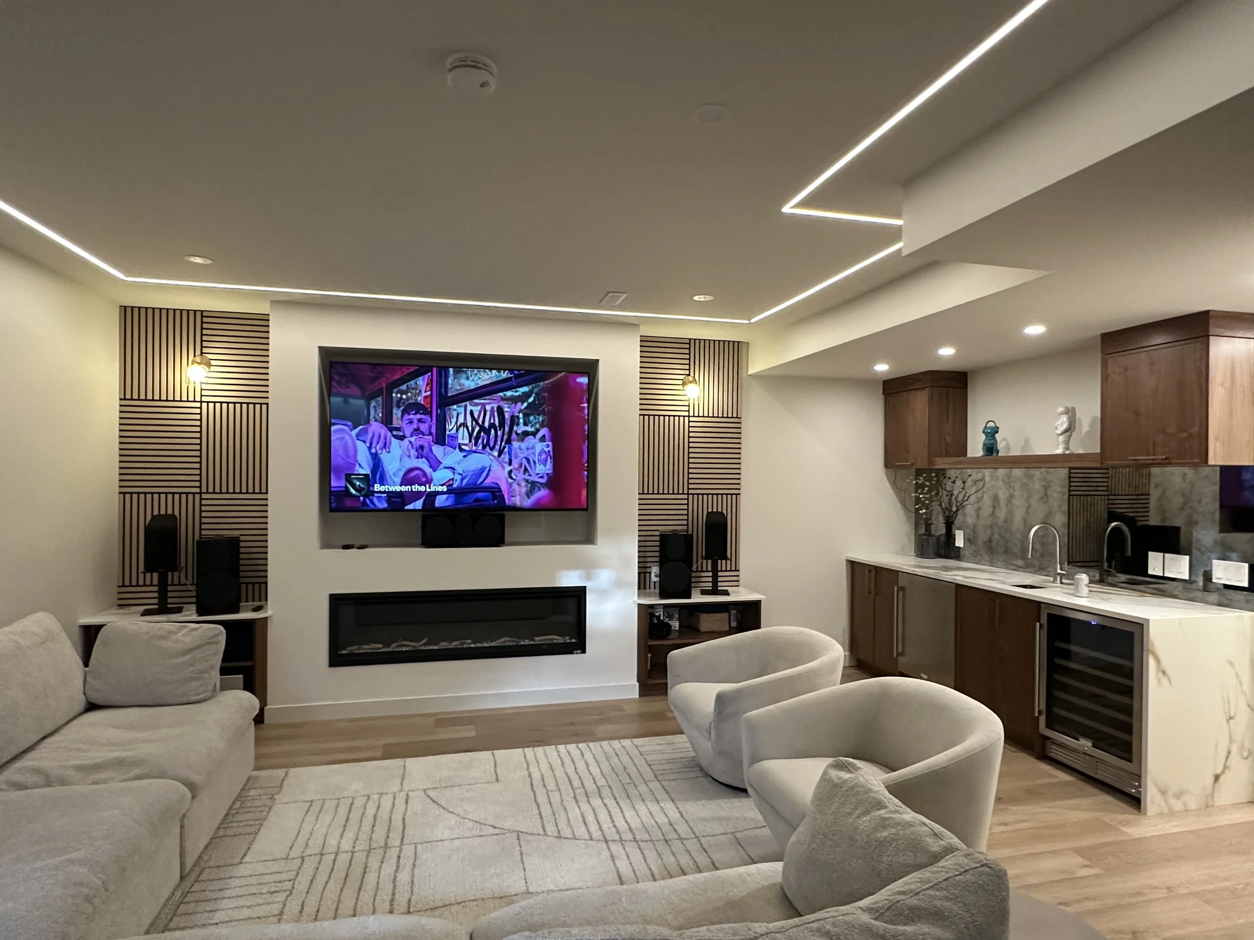 Calgary Renovation Contractor modern basement with custom bar, built-in fireplace, LED lighting, and luxury home theatre setup.