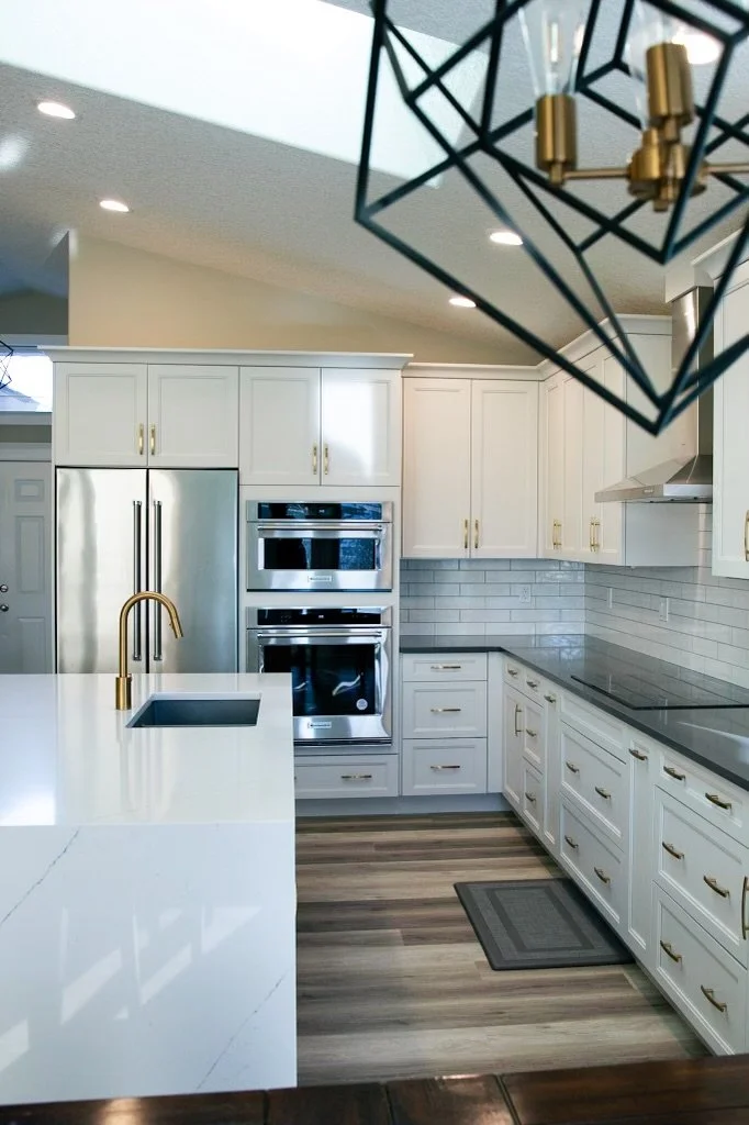After renovation - modern white shaker cabinets, quartz waterfall island, and brass fixtures in Royal Oak kitchen remodel.