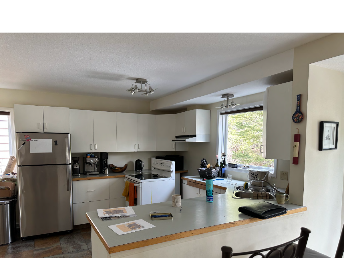 Before Canmore kitchen renovation with outdated white cabinets, laminate countertops, and small appliances