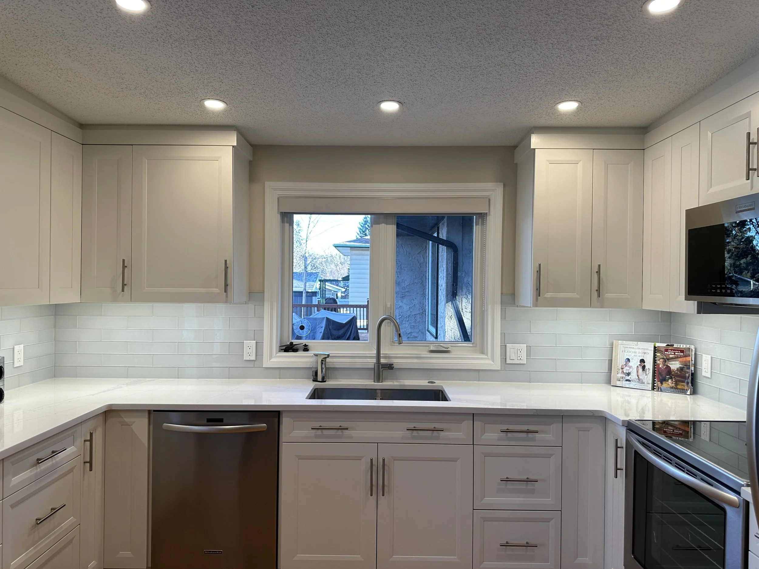 Calgary kitchen after renovation with modern white shaker cabinets, quartz countertops, and updated LED lighting