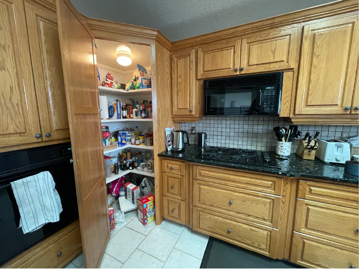 Before kitchen renovation in Royal Oak Calgary with oak cabinetry, black countertops, and tile flooring.
