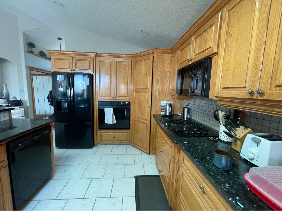 Before renovation - outdated oak cabinets with black appliances and dark granite countertops in Royal Oak kitchen.