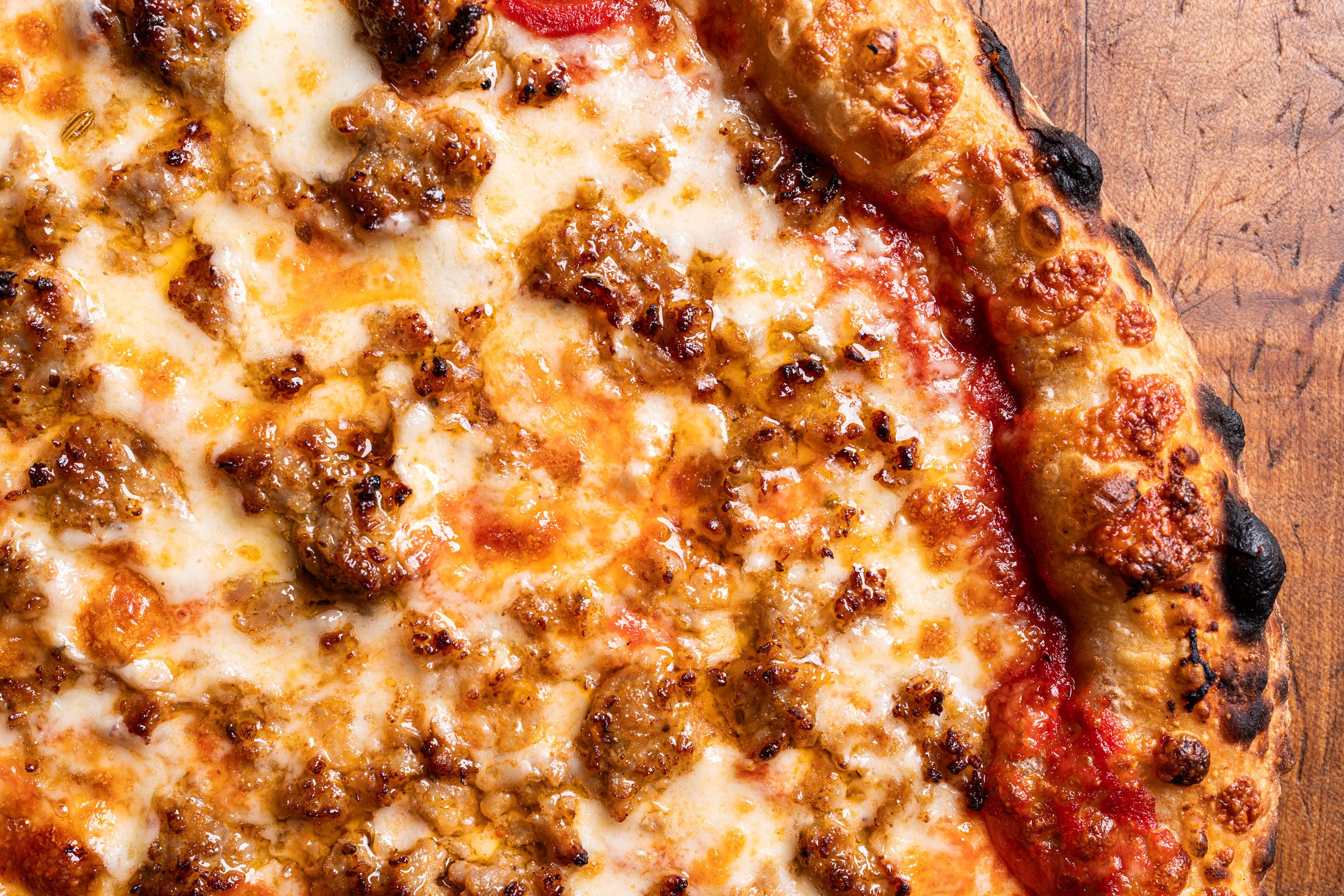 close up view of cheeses, sourdough crust, and sausage
