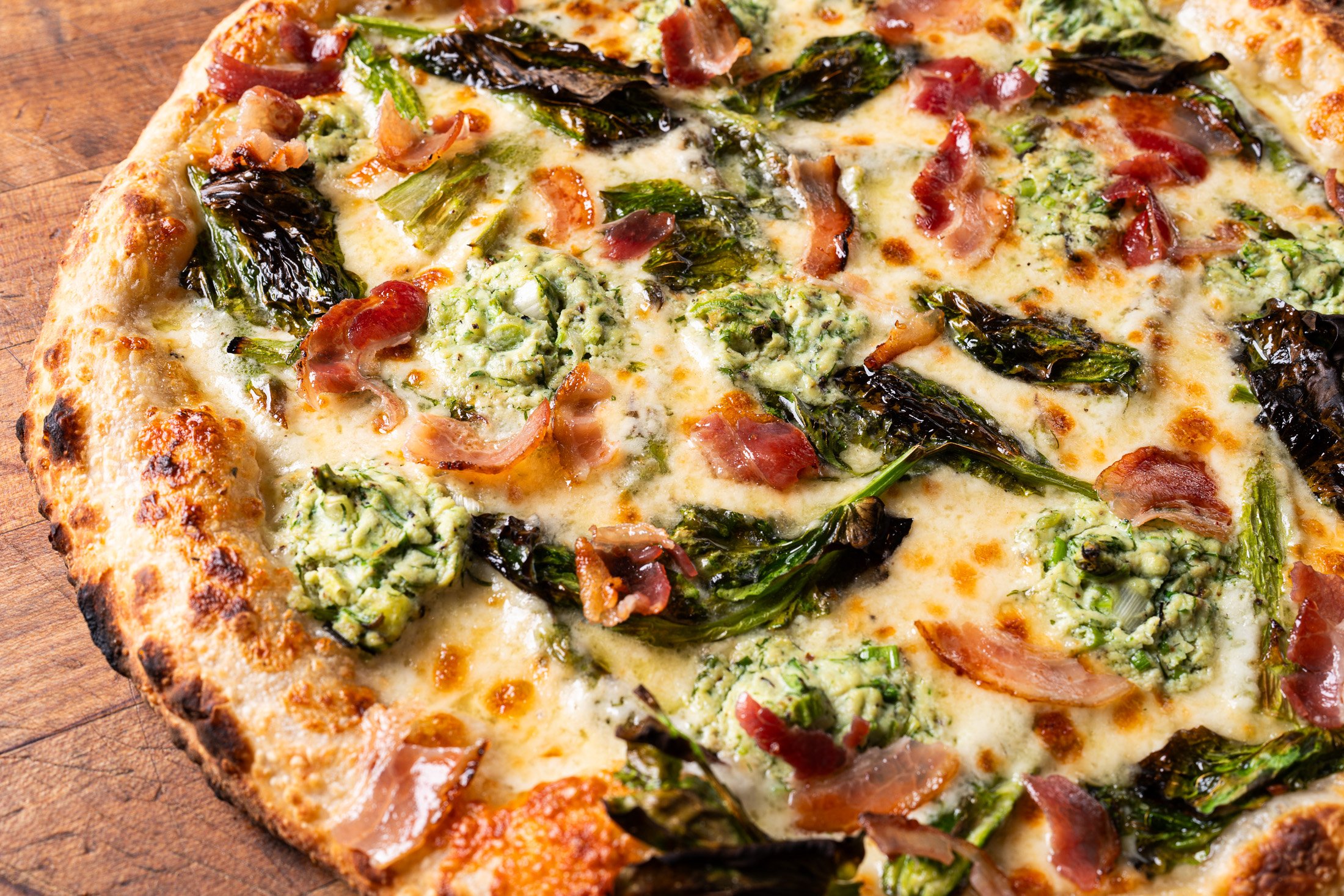 detail image of the dear mama pizza showing charred greens and cheese