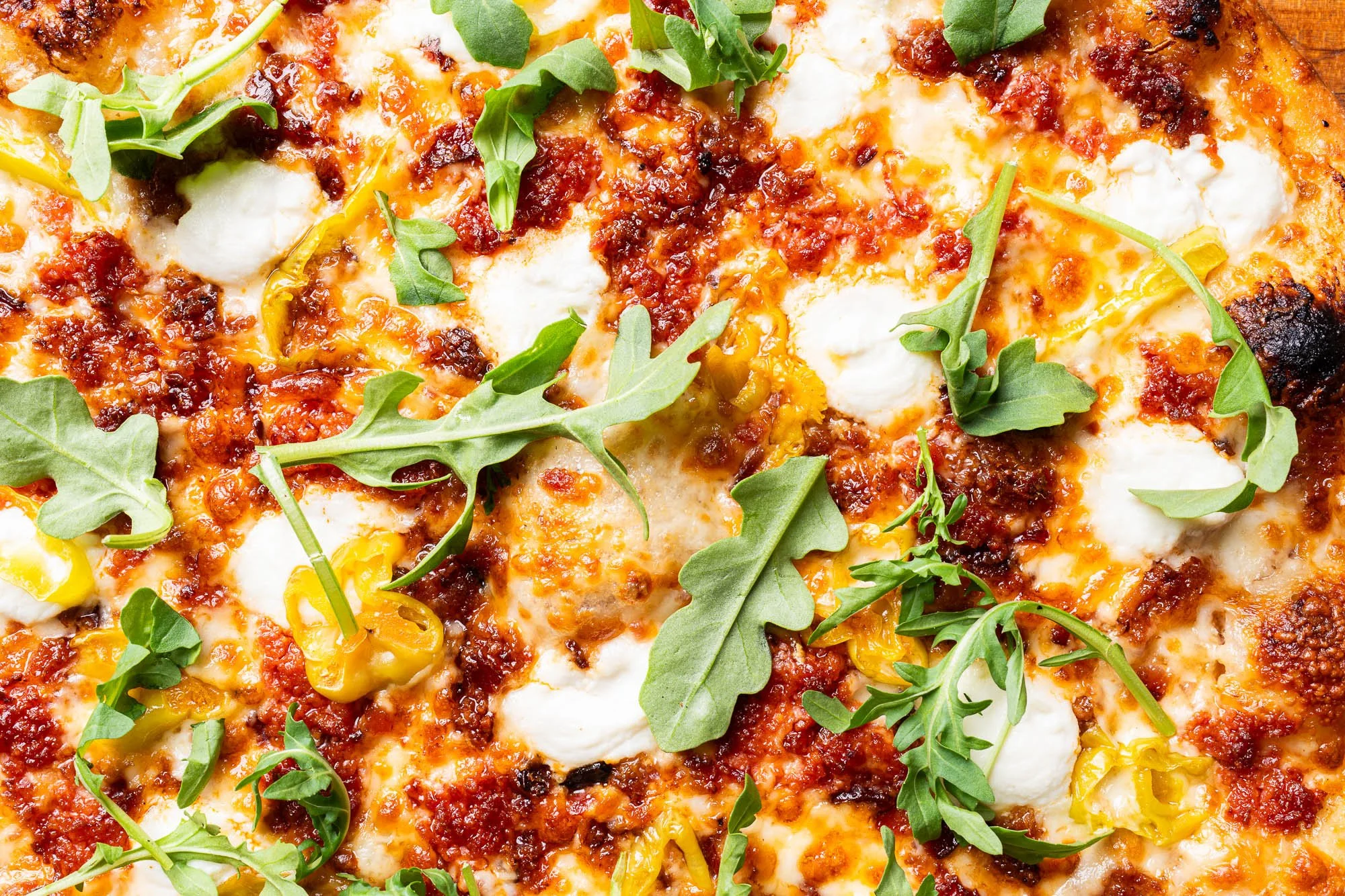 detailed view of the Notorious P.I.G. special with ground pepperoni, bacon jam, mozzarella, ricotta and arugula.
