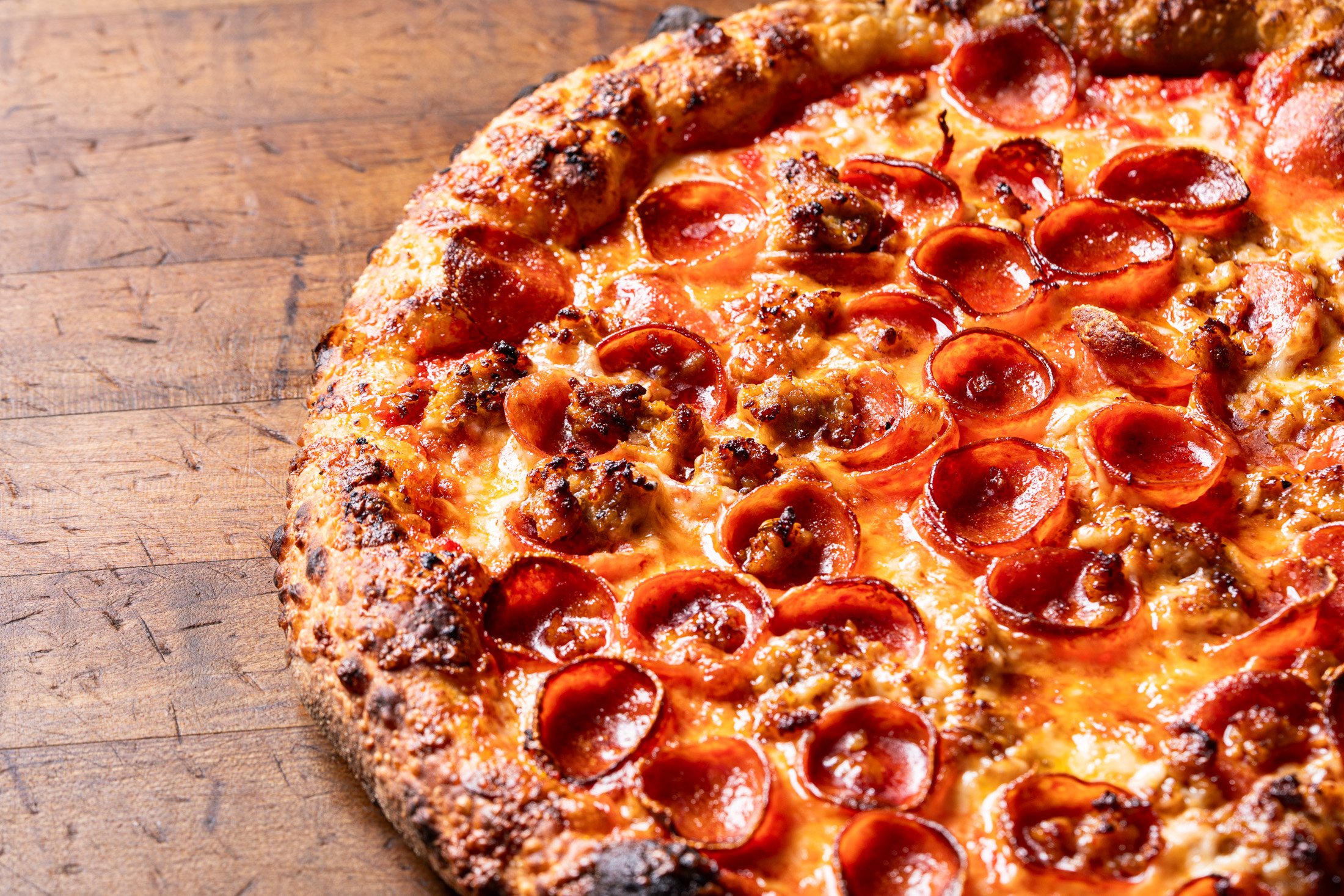 close up view of sourdough crust, cheese, sausage and pepperoni