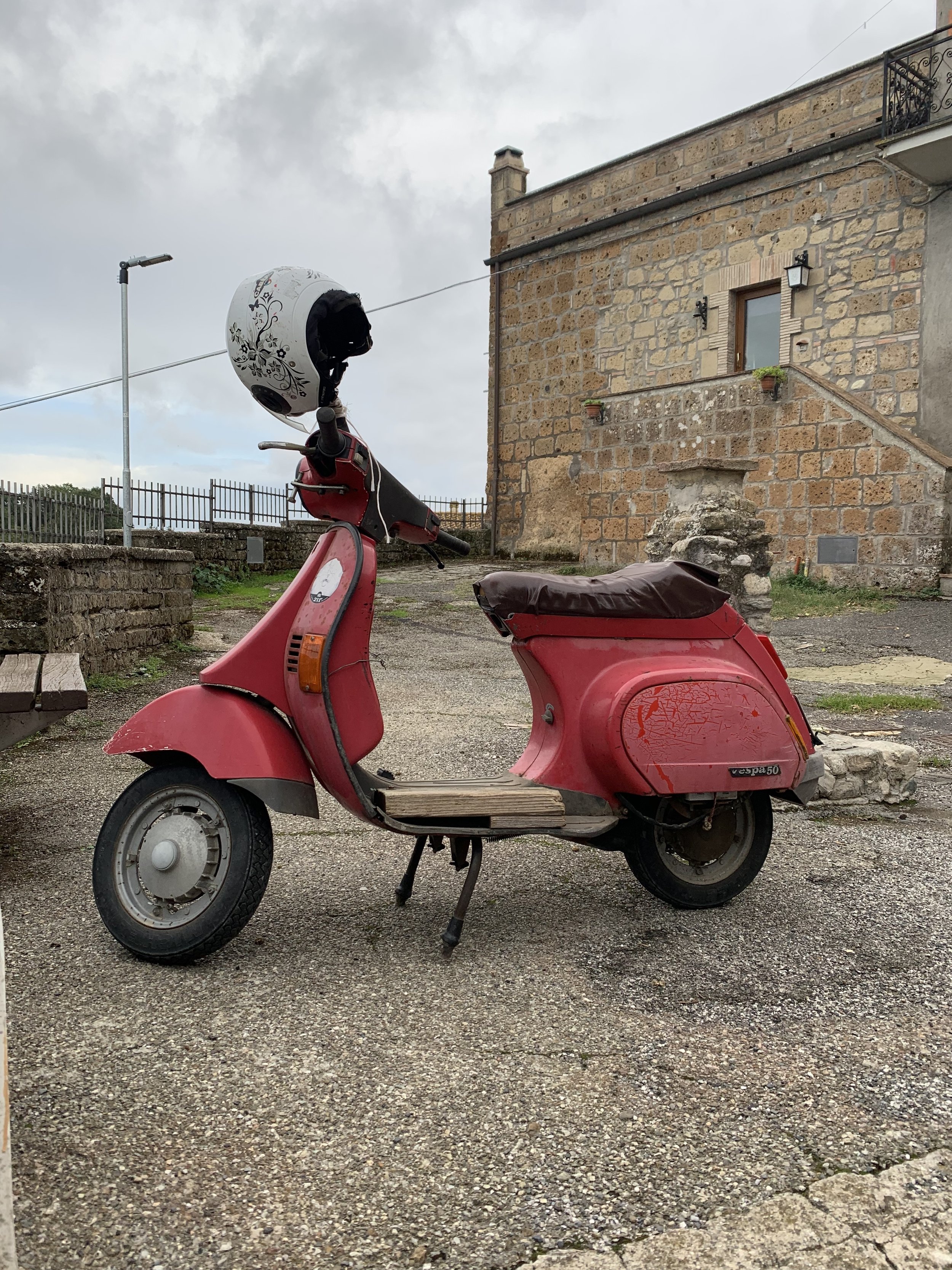 Vespa rossa parcheggiata davanti a un edificio in pietra, per il progetto ME.CO.