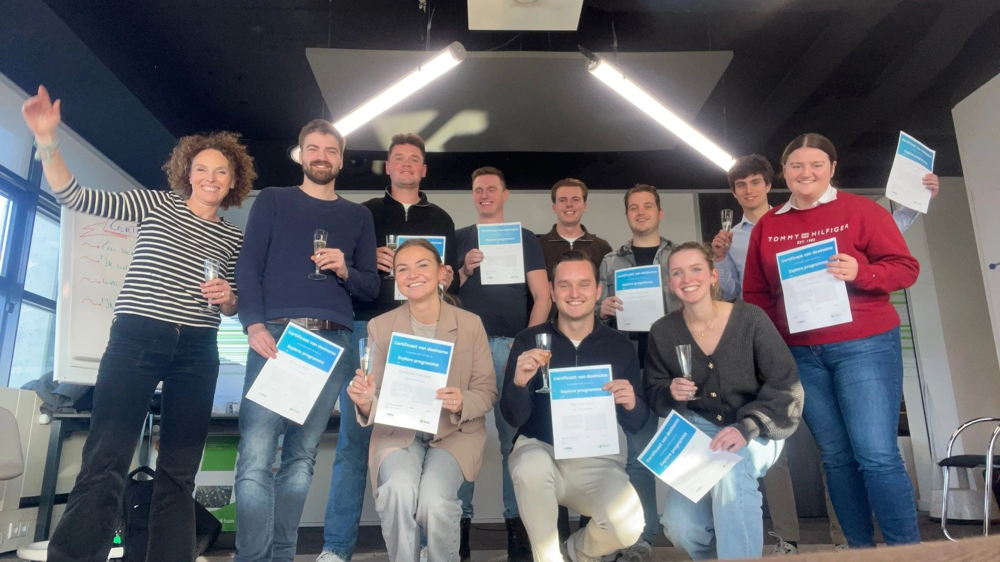 Groep mensen die aan het einde van een cursus of opleiding hun certificaat ontvangen, vieren feest met wijn en los enthousiasme.