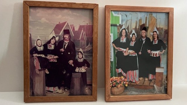 Twee ingelijste foto's van groepen mensen in traditionele kleding, vermoedelijk uit Nederland, met houten frames.