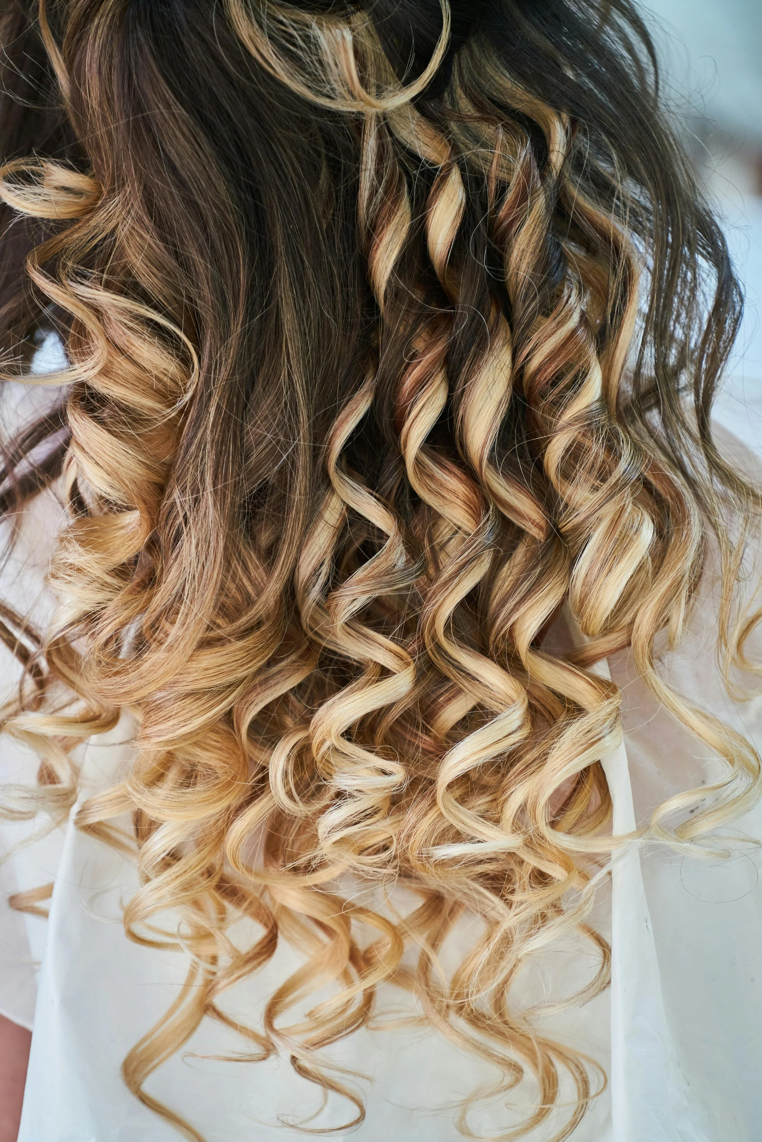 Close-up of long, curly hair with dark roots and blonde ends.