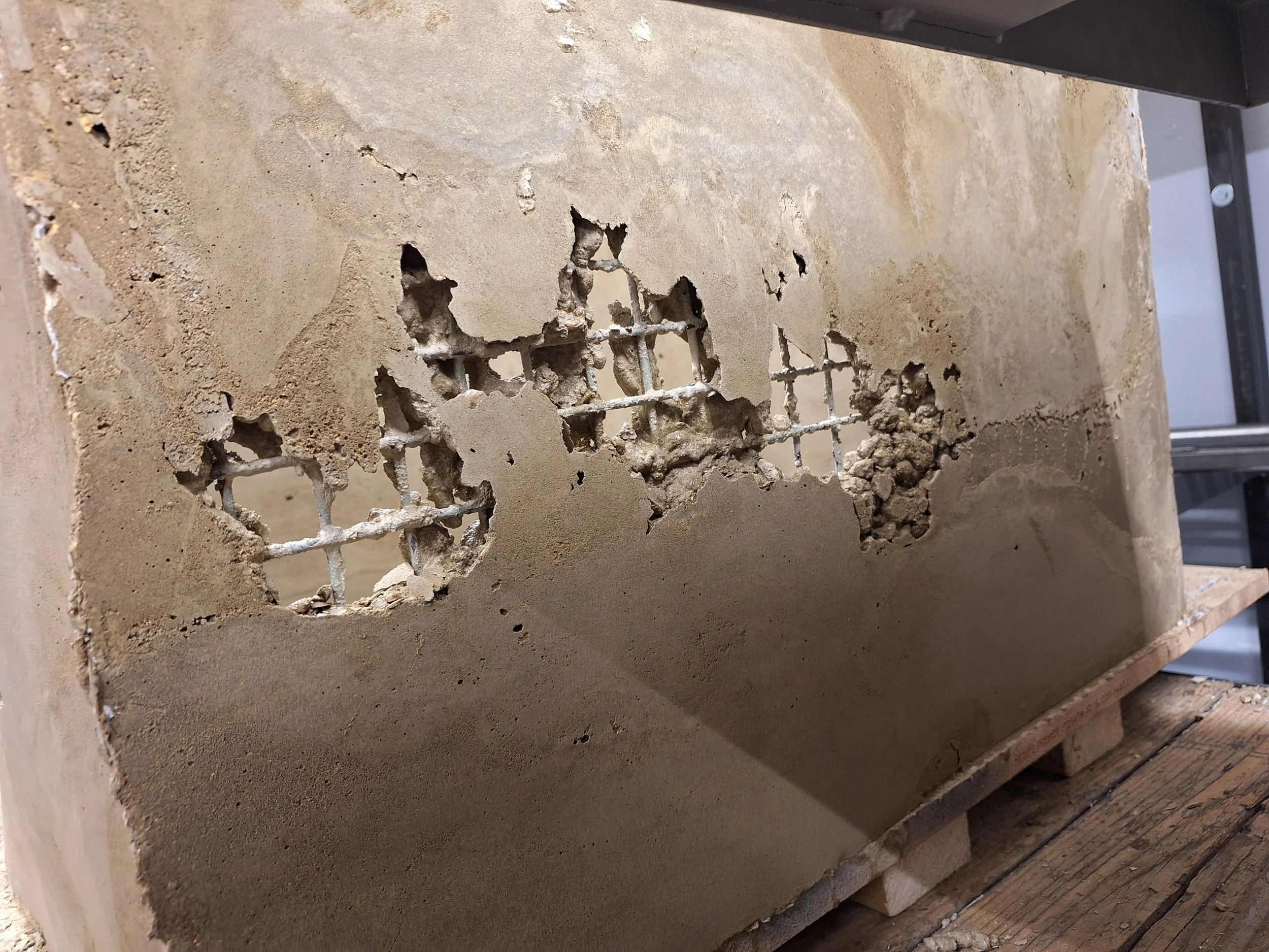 These voids were repaired by filling with a sharp sand and cement mix. Some formwork was reattached to the interior and exterior faces before filling from a small hole at the outside top of the void. Copious vibration from the sander resulted in a pr